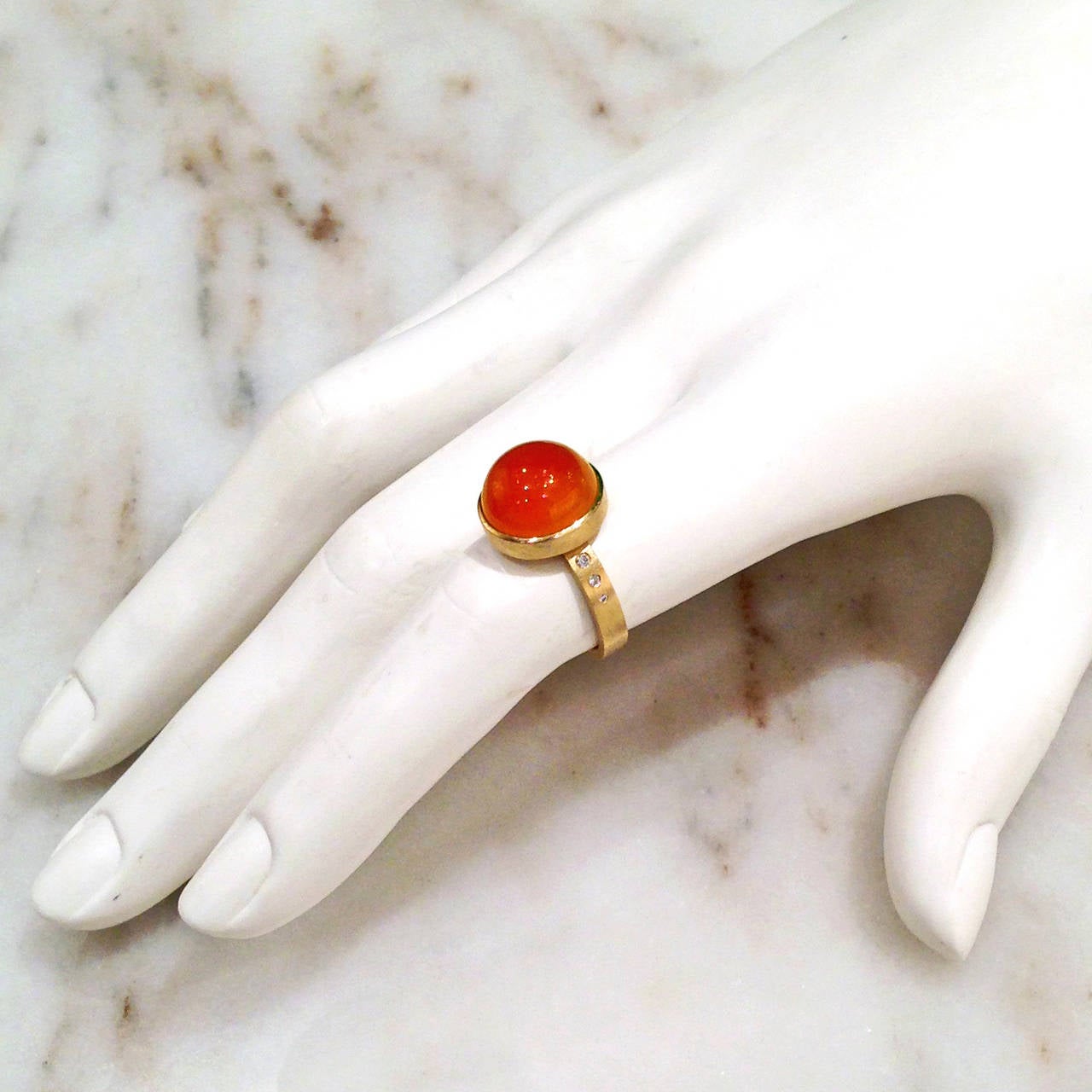 One-of-a-Kind Button Ring handcrafted in 18k yellow gold by the award-winning  jewelry artist, Robin Waynee. The ring features a 7.56 carat cabochon-cut tangerine chalcedony and 0.05 carats of ascending bezel-set vs1 white diamonds perfectly
