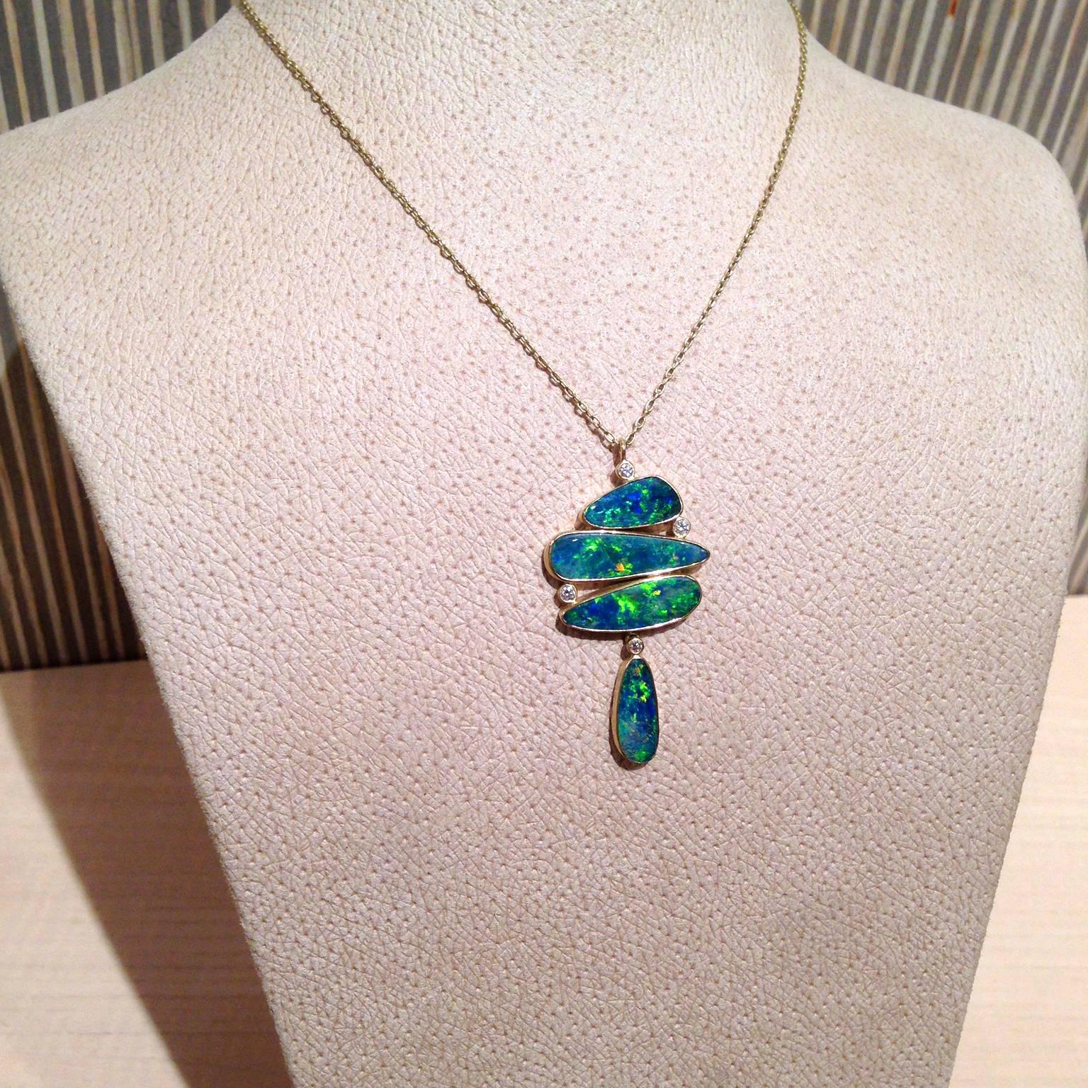 One-of-a-Kind Necklace hancrafted by Kothari Designs in matte-finished 18k yellow gold with four gorgeous boulder opals showcasing primarily blue and green color play with accent colors of orange, yellow, red, and pink. The opals are bezel-set in