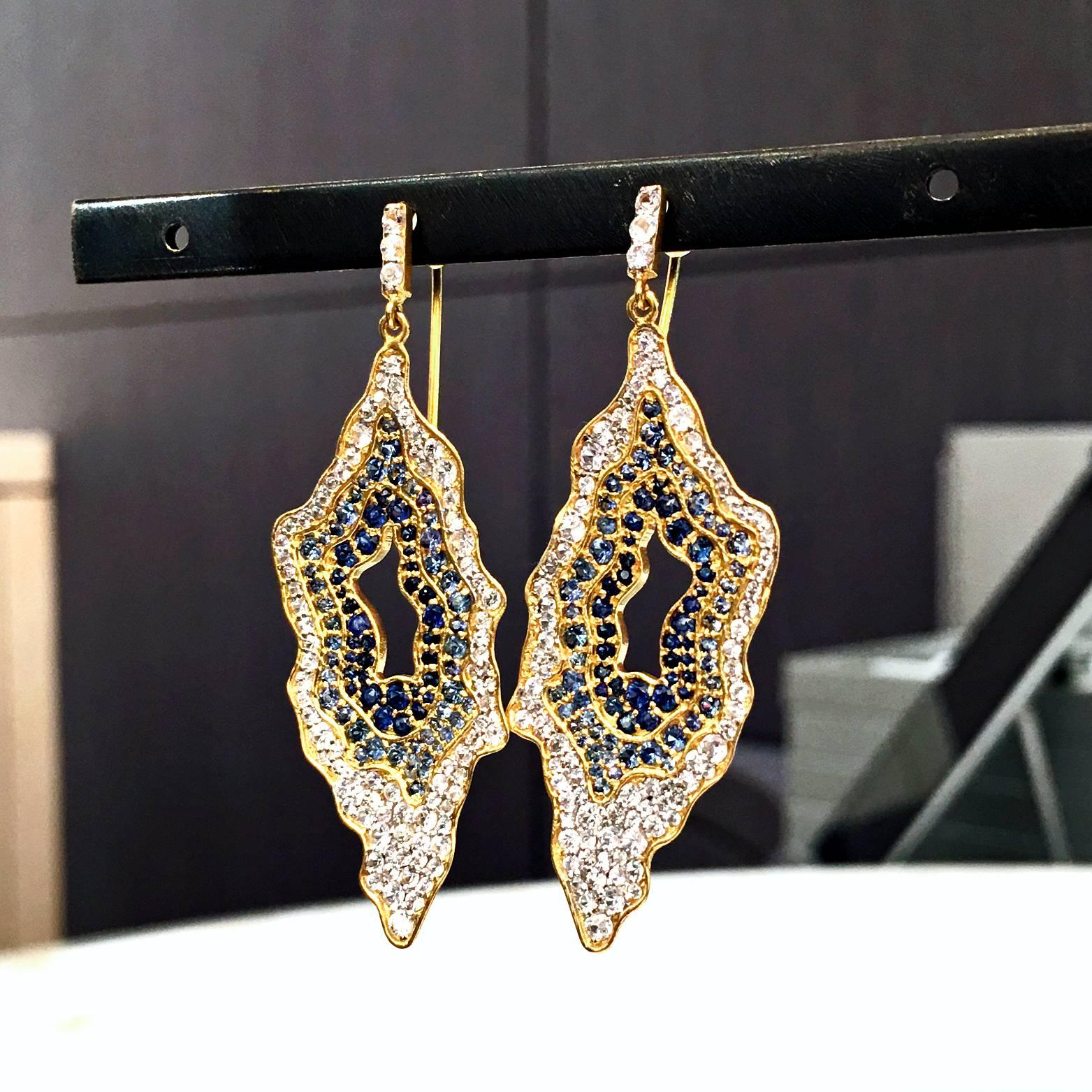 Snow Geode Earrings handcrafted in matte-finished 18k yellow gold with dangling geode elements set with blue sapphires in assorted tones and shimmering white sapphires and attached to 18k yellow gold wires with white sapphire accents. Incredible