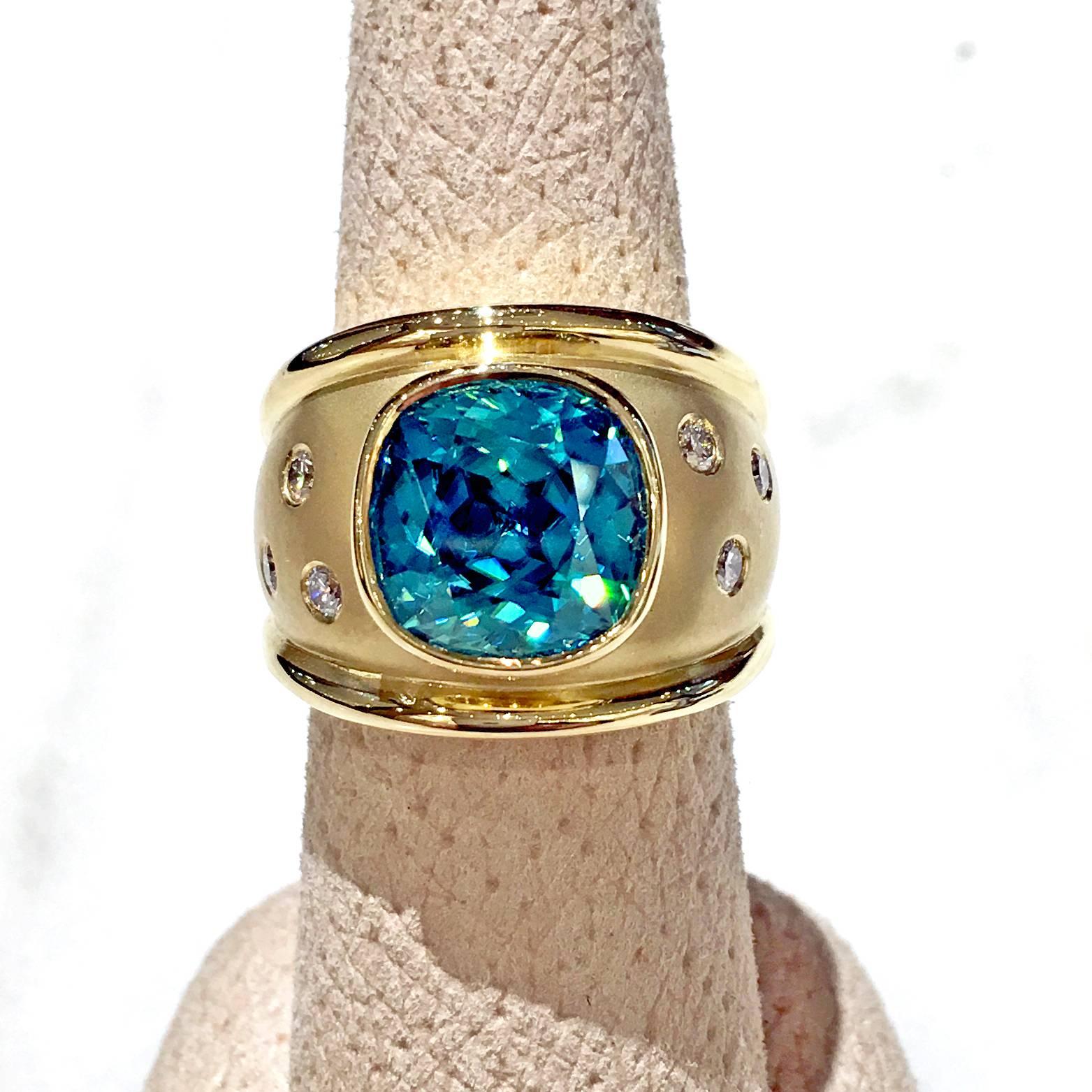 One of a Kind Ring handcrafted in matte-finished and polished 18.5k yellow gold with an incredible 10.44 carat Vietnamese greenish-blue zircon and accented with six bezel-set white round brilliant-cut diamonds (F/vs1) totaling 0.32 carats. Size 7.25