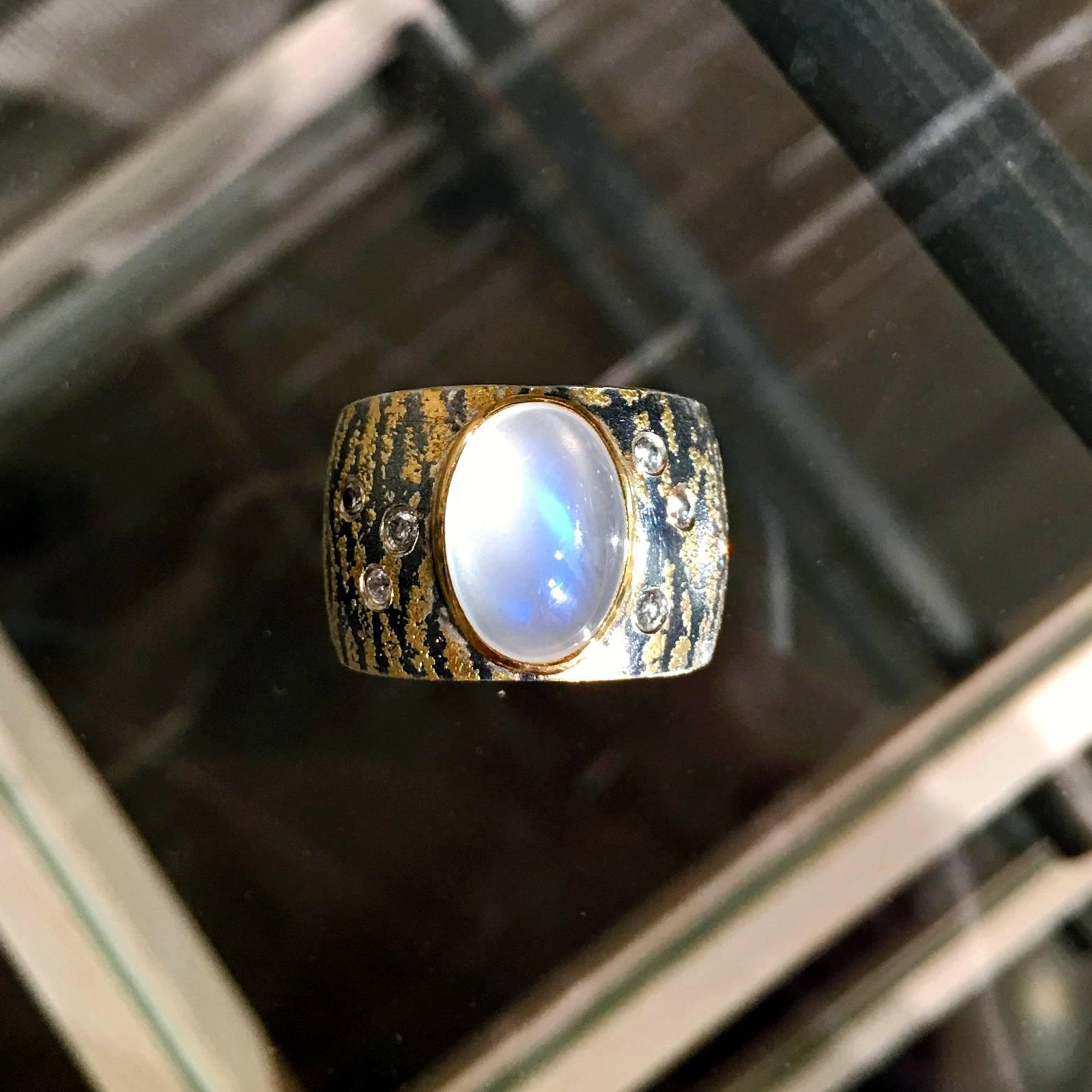 One-of-a-Kind Ring handcrafted by award-winning jewelry artist Atelier Zobel (Peter Schmid) in 24k gold, 22k yellow gold, and oxidized sterling silver showcasing a stunning silvery-white moonstone with intense, beautiful flashes of violet and blue,