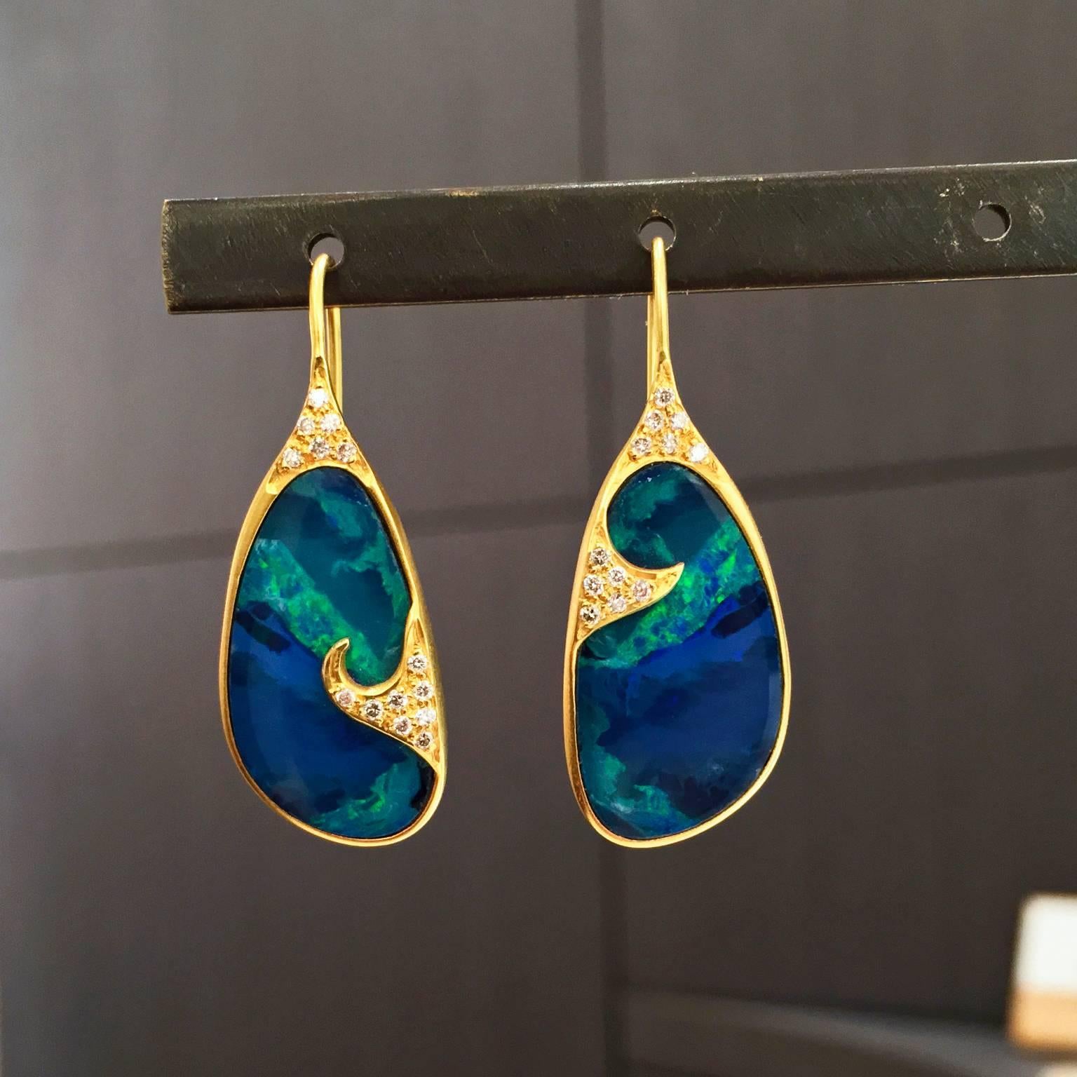 One-of-a-Kind Wave Earrings handcrafted in matte-finished 18k yellow gold showcasing two hand-cut and hand-polished boulder opal doublets displaying primarily blue and green color with flashes of orange, red, and yellow. Earrings are accented by