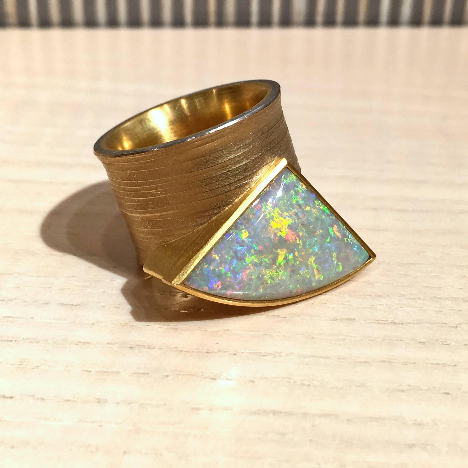 One-of-a-Kind ring handcrafted in 21k yellow gold and platinum with a gorgeous custom cut and polished 9.55 carat opal exhibiting a flashfire and pinfire pattern showcasing primarily orange, red, and green flash with strong accents of violet, blue,