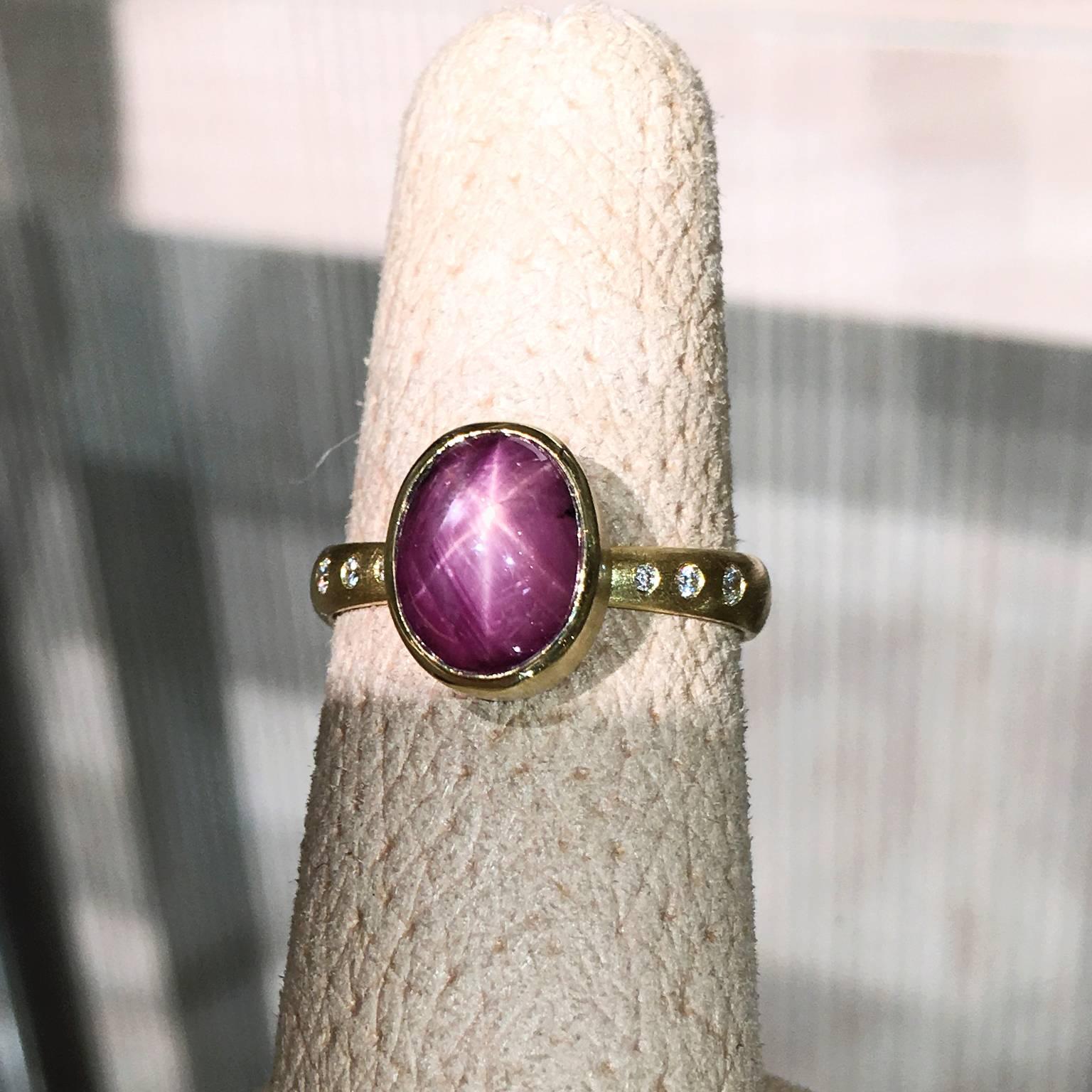 One-of-a-Kind Star Dome Ring handcrafted in matte-finished 18k yellow gold by Robin Waynee with an oval cabochon-cut 5.35 carat purplish-red six-ray star ruby bezel-set and accented with six round brilliant-cut E-F/vs1 white diamonds totaling 0.07