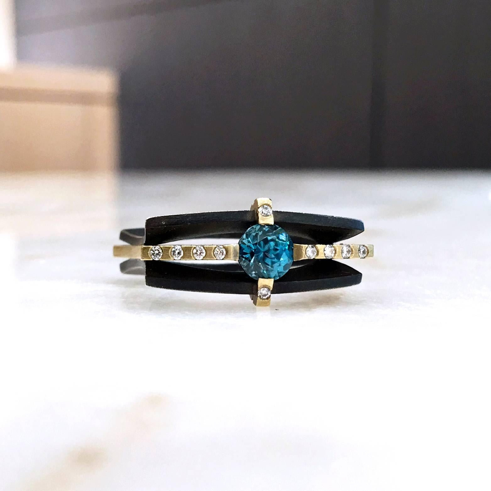 One-of-a-Kind Ring handcrafted by Robin Waynee with two curved and matte finished oxidized sterling silver bands interconnected with a matte finished 18k yellow gold center band. The ring showcases a spectacular 1.18 carat brilliant blue zircon