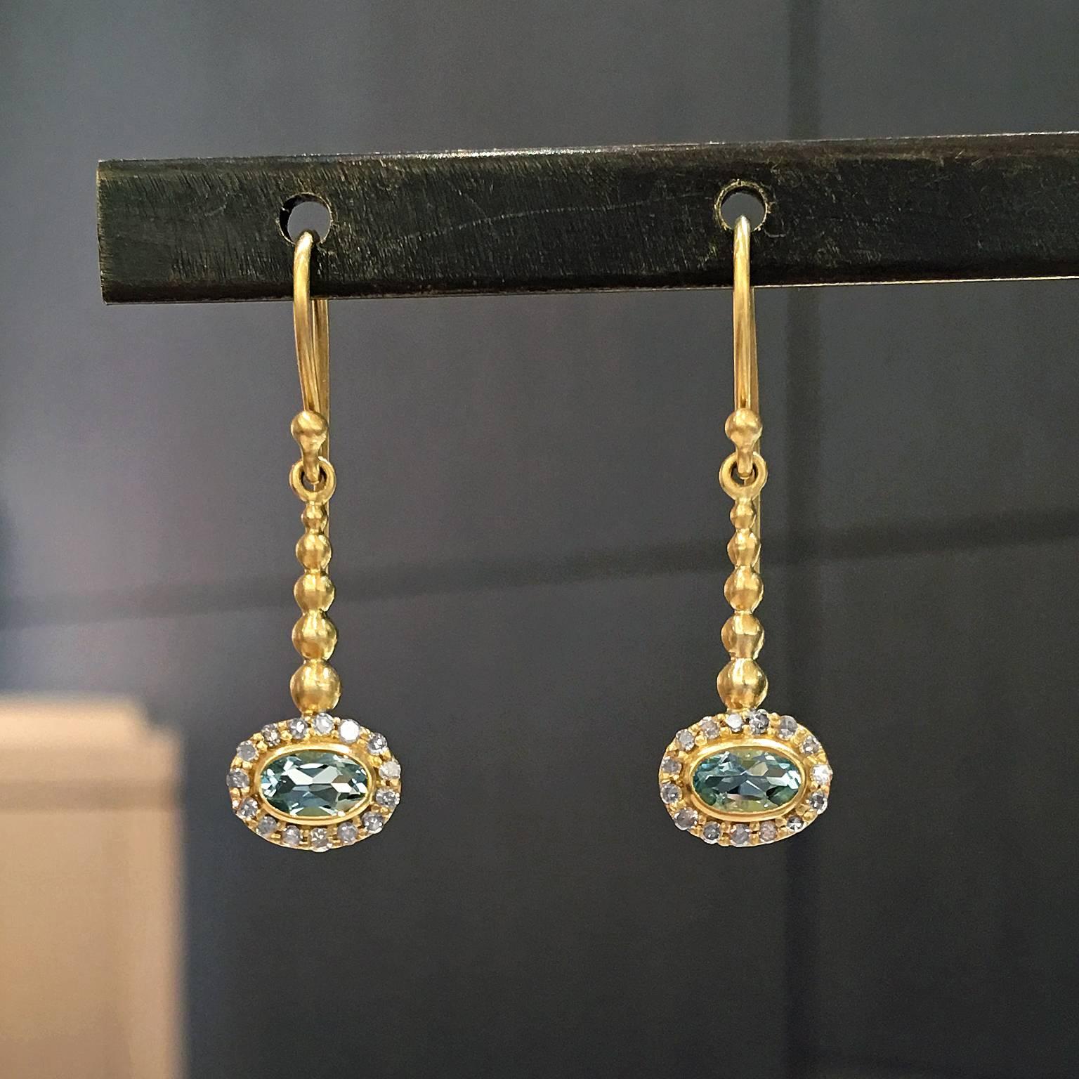 One of a Kind Pendulum Earrings handcrafted by jewelry designer Tej Kothari in matte-finished 18k yellow gold with two greenish-blue oval faceted aquamarines bezel-set and surrounded with 0.16 carats of shimmering diamonds.