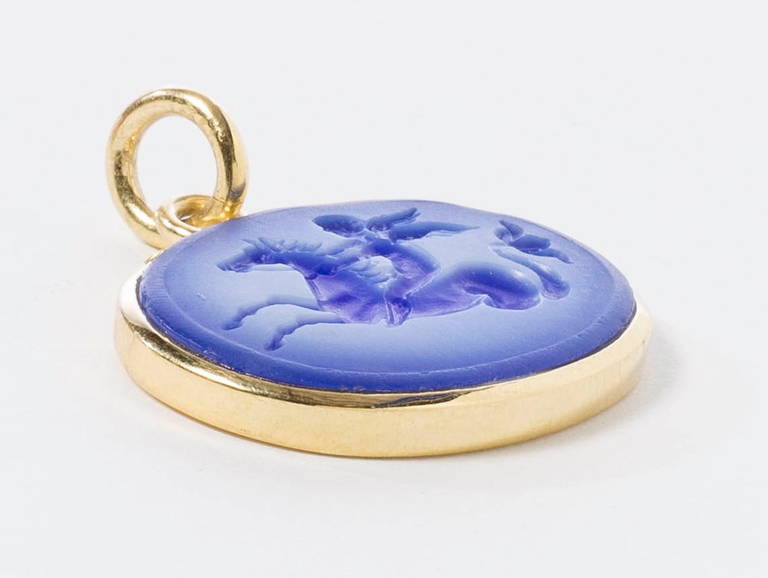 Blue agate hand engraved Eros riding on a sea horse. Set in an 18 karat yellow polished gold frame and loop. Available in 2 sizes : Large (shown here) stone size 25mmx18mmx2.6mm.      Medium stone size 25mmx15mmx2.4mm
