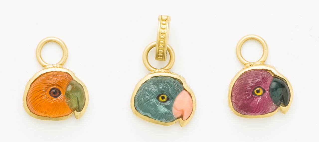 Lovely hand carved blue tourmaline parrot head pendant with pink opal beak in profile set in 18 karat brushed yellow gold frame with loop.  Included with a detachable hand cast 18K brushed gold beaded enhancer. Painted crystal eye.
By Master