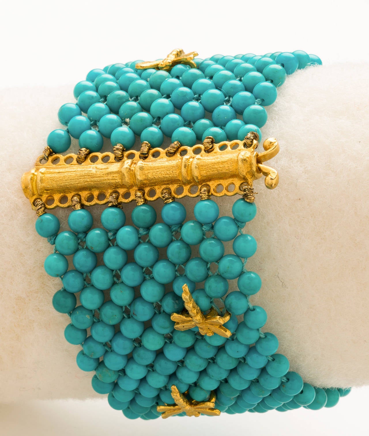 Beautifully & intricately hand woven turquoise beads in a multi-strand bracelet set with six 18 karat brushed yellow gold dragonflies and brushed gold bamboo style closure.Turquoise beads- 3mm. Length 7 inches & width 1 1/2 inches.