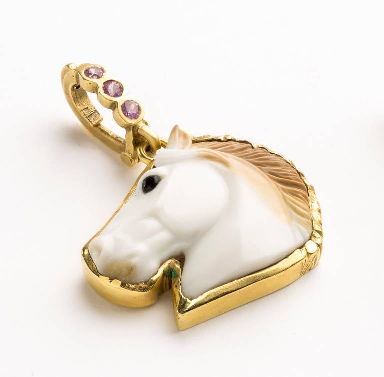 Hand carved natural Cocholong horse head pendant with light brown mane (by master Idar-Oberstein carver) set in an 18karat gold surround with .30cts pink sapphire set in a gold detachable bail.

28x22x5mm stone size