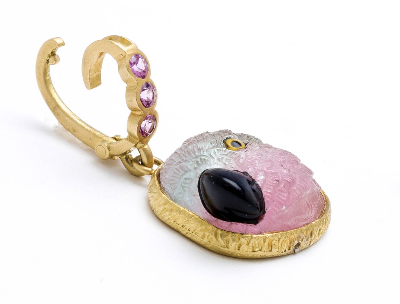 Hand carved watermelon tourmaline parrot head with delicately feathered detail (by Master Idar-Oberstein carver) onyx beak and hand painted crystal eye. Set in hand crafted bezel feather design in 18 karat brushed gold with pink sapphire (.30carats)