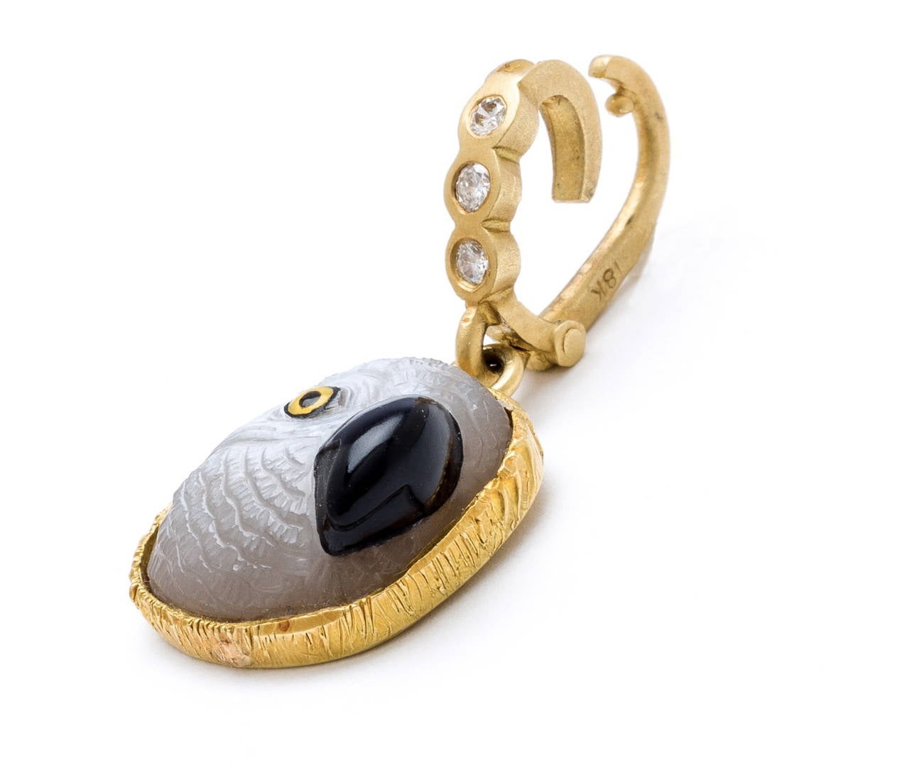 Moonstone hand carved parrot head with beautiful feathered detail (by Master Idar-Oberstein carver) onyx beak and hand painted crystal eye. Set in hand crafted bezel feather design in 18 karat brushed gold with gold and diamond (.30carats) enhancer