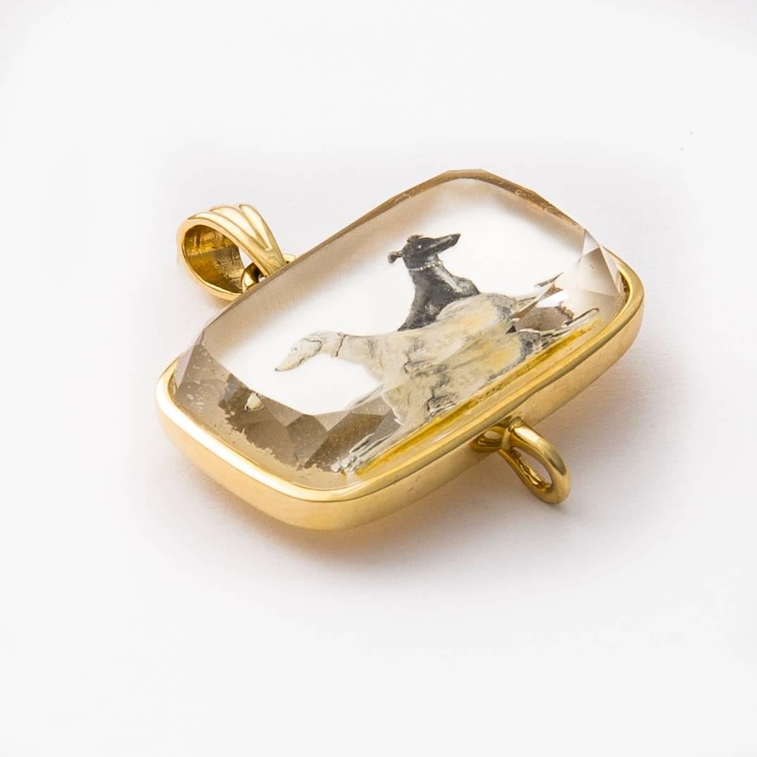 Beautifully detailed hand painted reverse crystal greyhound portrait pendant backed with Mother-of-pearl.  This deep beveled stone is set in 18 karat polished gold frame with detachable 7mm gold capped pearl. 
 Created by Master Idar-Oberstein