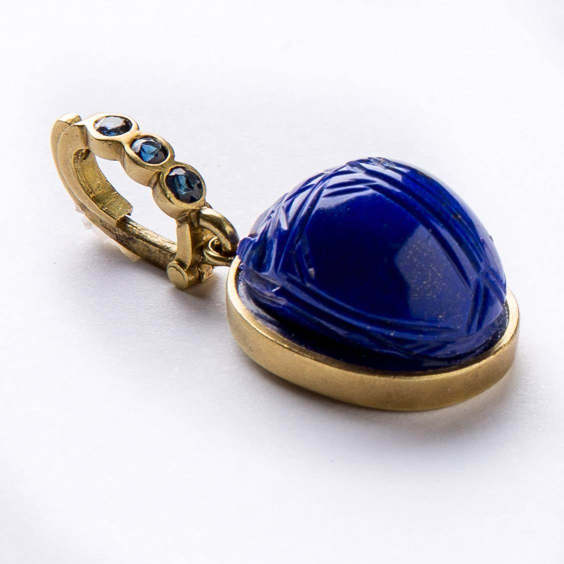 Lovely hand carved scarab pendant in natural lapis lazuli stone (by Master Idar-Oberstein carver). Pendant is set in 18 karat yellow brushed gold frame with gold detachable enhancer with deep blue sapphires (.30cts).