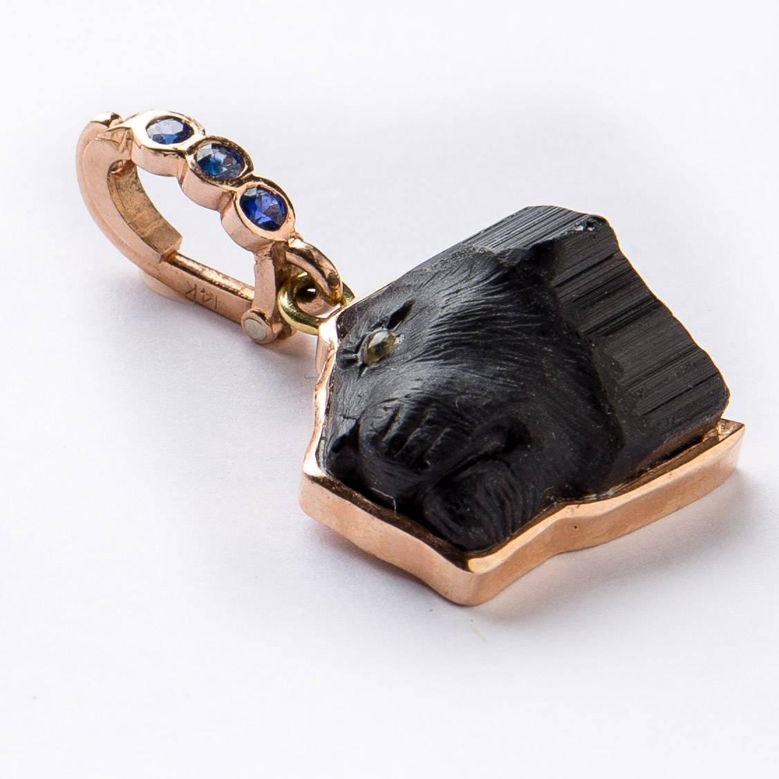 Unusual custom hand carved black tourmaline lion's head in profile with painted crystal eye. Set in rose gold frame with rose gold .30 carat blue sapphire enhancer which opens to hang from your necklace.  Created by Master Idar-Oberstein carver.