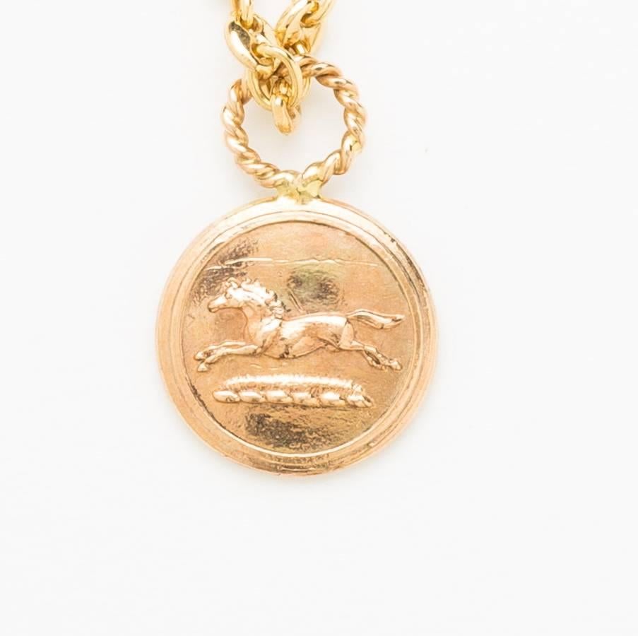 Stamped hunting horse 10 karat rose gold coin pendant in low relief dangling with 9mm round aquamarine bead with yellow gold loop. Included with 16