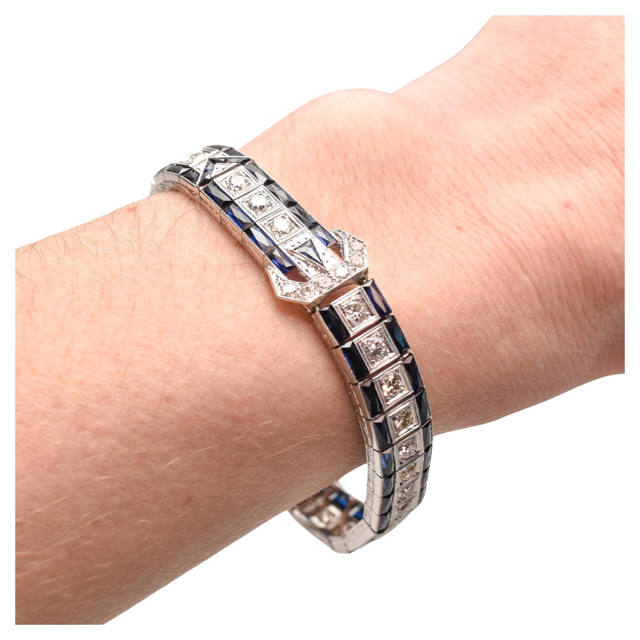A stunning platinum diamond & sapphire belt link bracelet. Features a dazzling single row of 32 natural OEC diamonds bordered by custom french baguette sapphires with a diamond and sapphire belt embellishment in the middle. The belt decoration