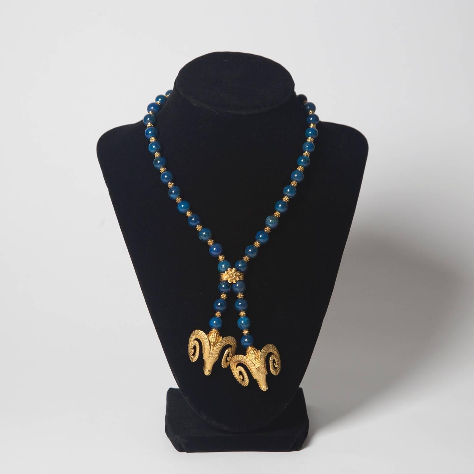 Beautiful lapis necklace inspired by a Grecian lariat style. Joined by a gold flower motif and conclude with two hanging ram heads, both in solid 18K gold. 