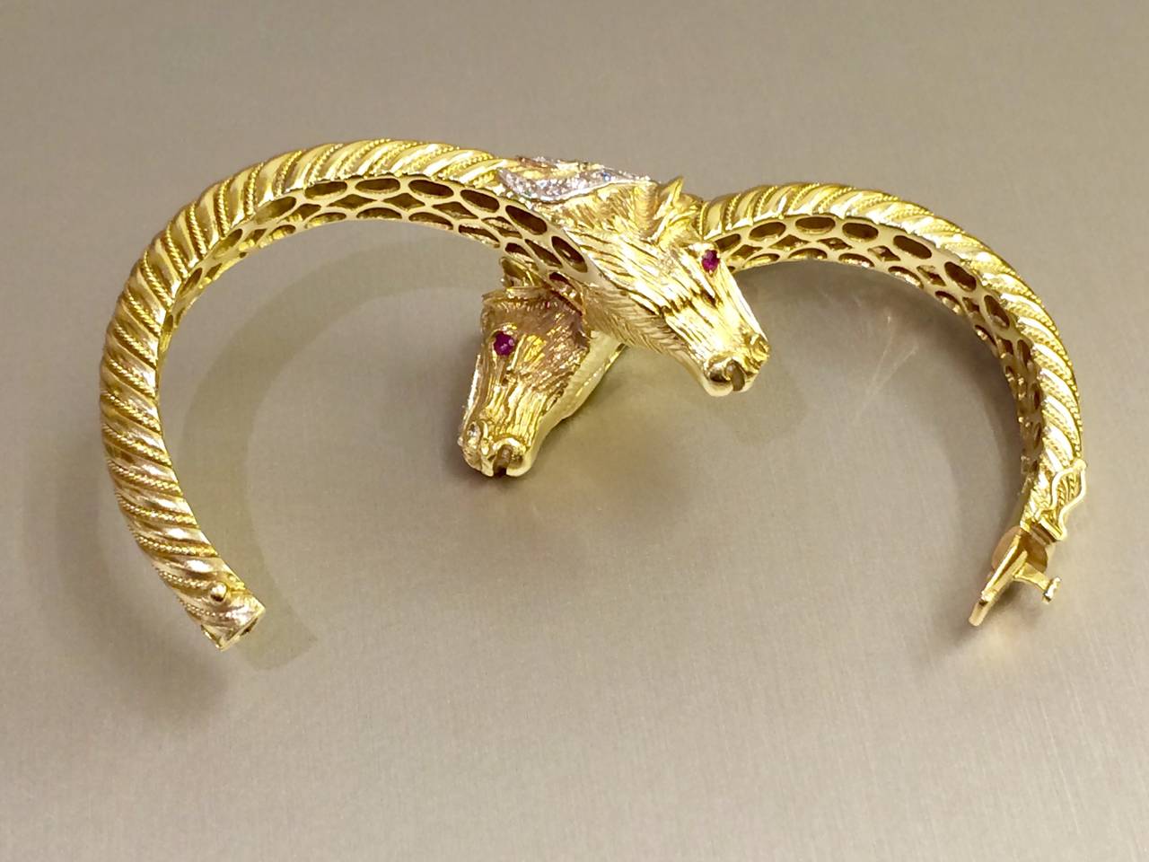 Open bangle in 18k yellow gold featuring two horse heads set with natural rubies and diamonds. Pre-Owned.
