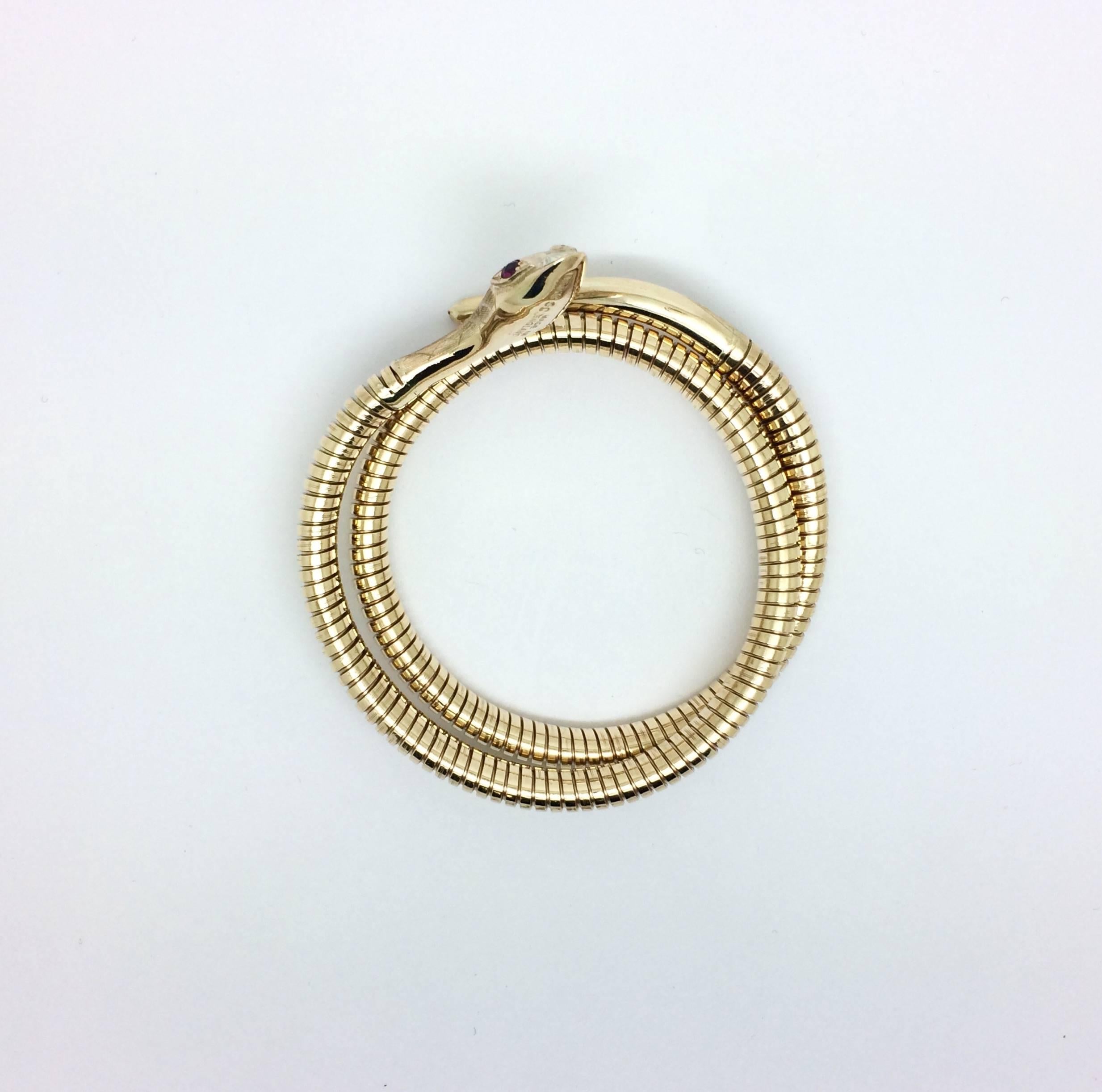 Snake coil 9kt yellow gold flexible bracelet, stamped BIRKS. A very comfortable piece to wear that is sure to receive compliments, from our estate with ruby eyes with intricate engraved head and tail. Approximately 28 grams in weight.