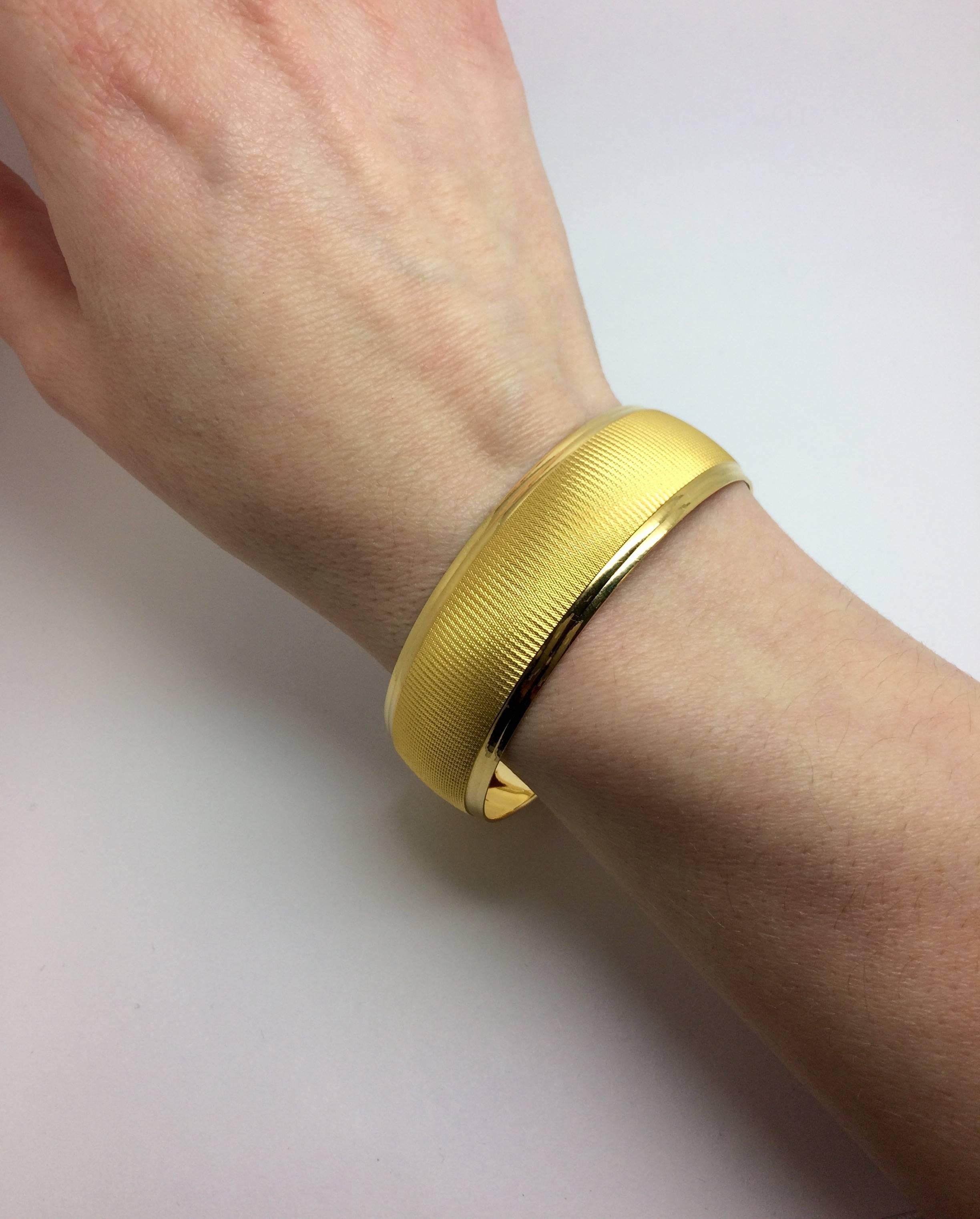 One 22kt yellow gold AU FINJA stamped bangle.  It is circular and has a classic double ridged edge on both sides with a patterned center. It is 6cm in diameter which fits a smaller wrist quite beautifully.
