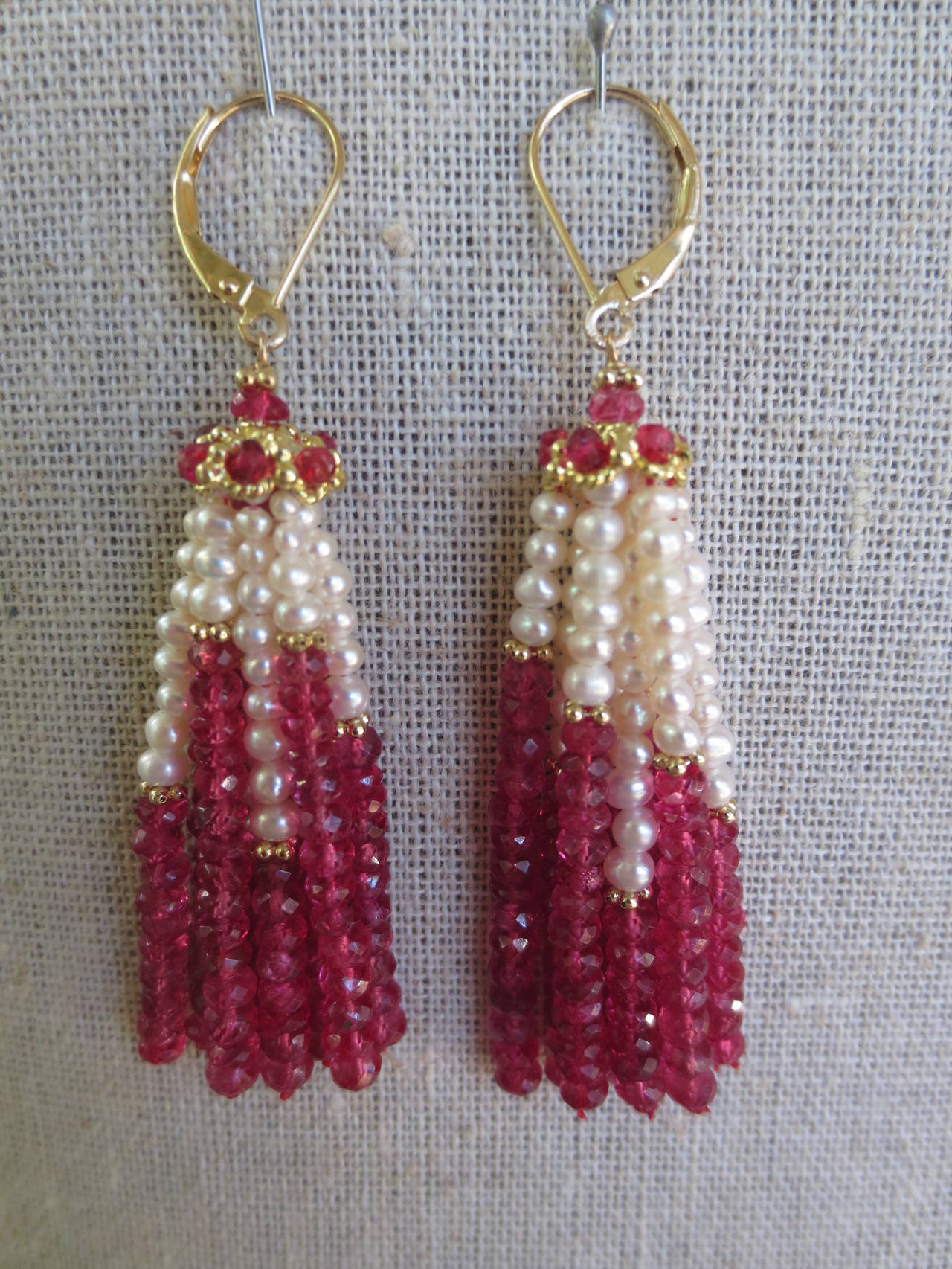 These elegant are the perfect gift.
Rich faceted ruby beads hang in gorgeous tassels along with cultured pearls, and accented with gold findings, creating a lightness to the lush tassel. The strands hang from a 14 k yellow gold cup detailed with