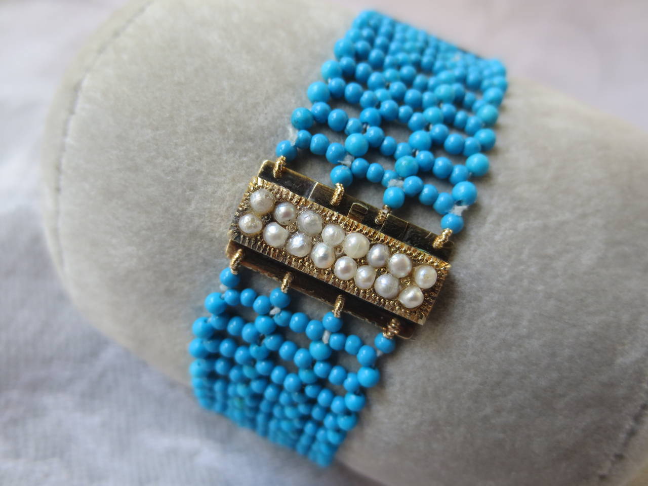 Intricately hand woven turquoise bracelet is unique and elegant. Accented with an antique gold and seed pearl centerpiece clasp, this is a classic and timeless piece.  The band is woven with 1.5 mm turquoise beads and the clasp is made of 14k gold