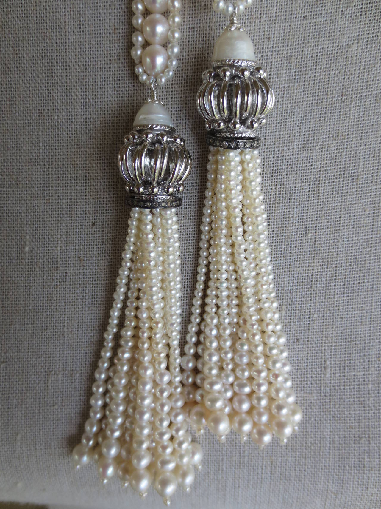 This white pearl sautoir necklace with rhodium plated silver beads and pearl tassels is reminiscent of the art deco style, with its long rope and elegant versatile design. The sautoir is made of handpicked glowing white pearls, ranging from 2 - 6.5