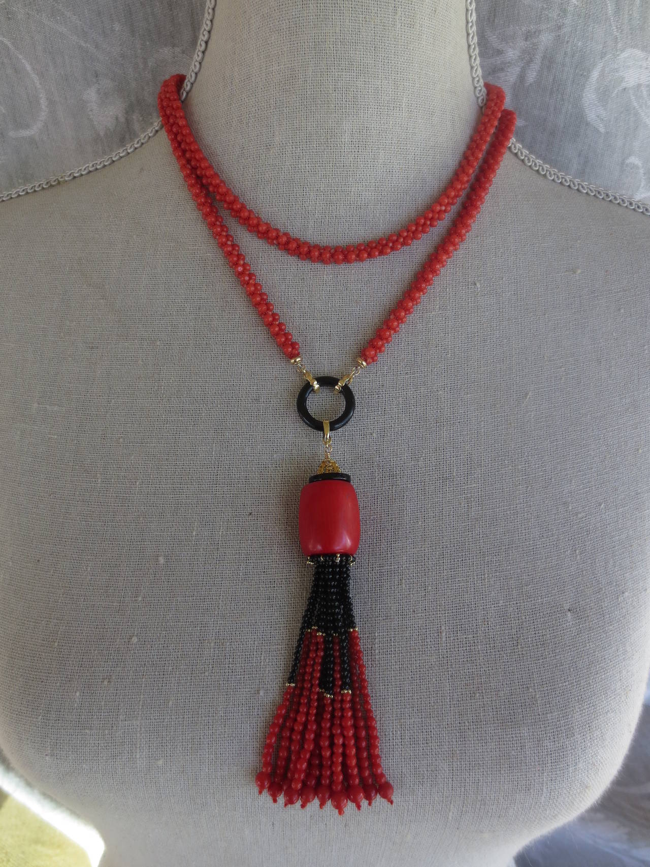 This gorgeous tassel is made of coral and onyx. Tassel strands are made of fine round coral onyx beads and drape from a large tubular coral bead accented with onyx and a yellow gold cup detailed with diamonds. Tassel measures approximately 4.5