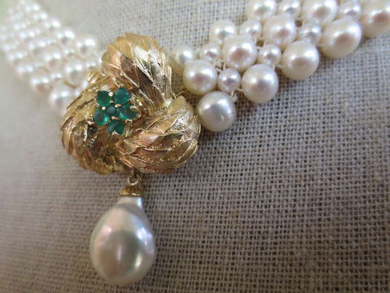 This hand woven with pearl necklace emerald and 14k yellow gold front facing clasp is a beautiful piece handcrafted by Marina J. The necklace is accented by a 14k yellow gold knot-like centerpiece that also serves as the necklace's clasp. In the