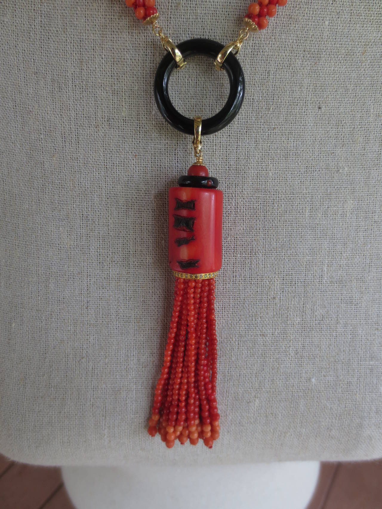 This gorgeous tassel is made of coral beads of different tone. Tassel strands are made of fine round coral beads and drape from a large tubular Middle Eastern old coral bead accented with onyx and a yellow gold rondelle detailed with diamonds. Ends