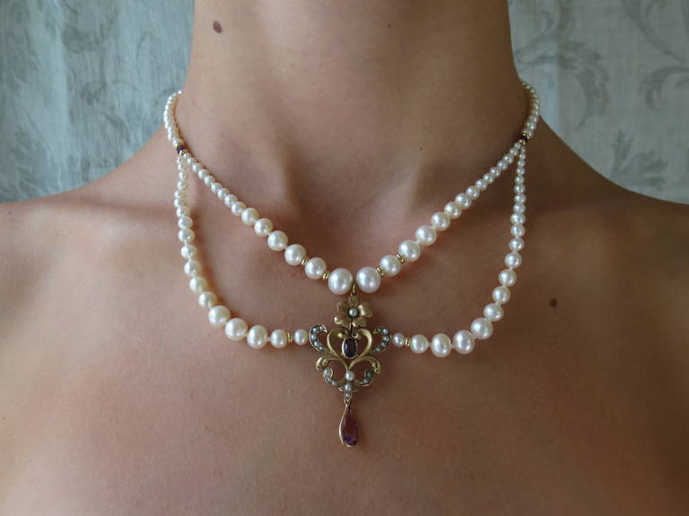 This romantic pearl draped necklace with an amethyst floral gold centerpiece and 14 k gold clasp is perfect for special occasions. The graduated drapes create an ethereal effect, giving a lightness to the necklace. The centerpiece was created from a