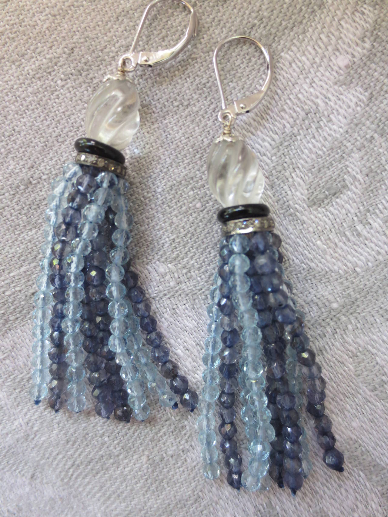 These elegant earrings are made of tiny hand selected iolite and aquamarine faceted beads. The strands are made of 2mm beads  to create a light and ethereal effect. The strands hang from a larger antique carved quartz bead accented by tiny a black