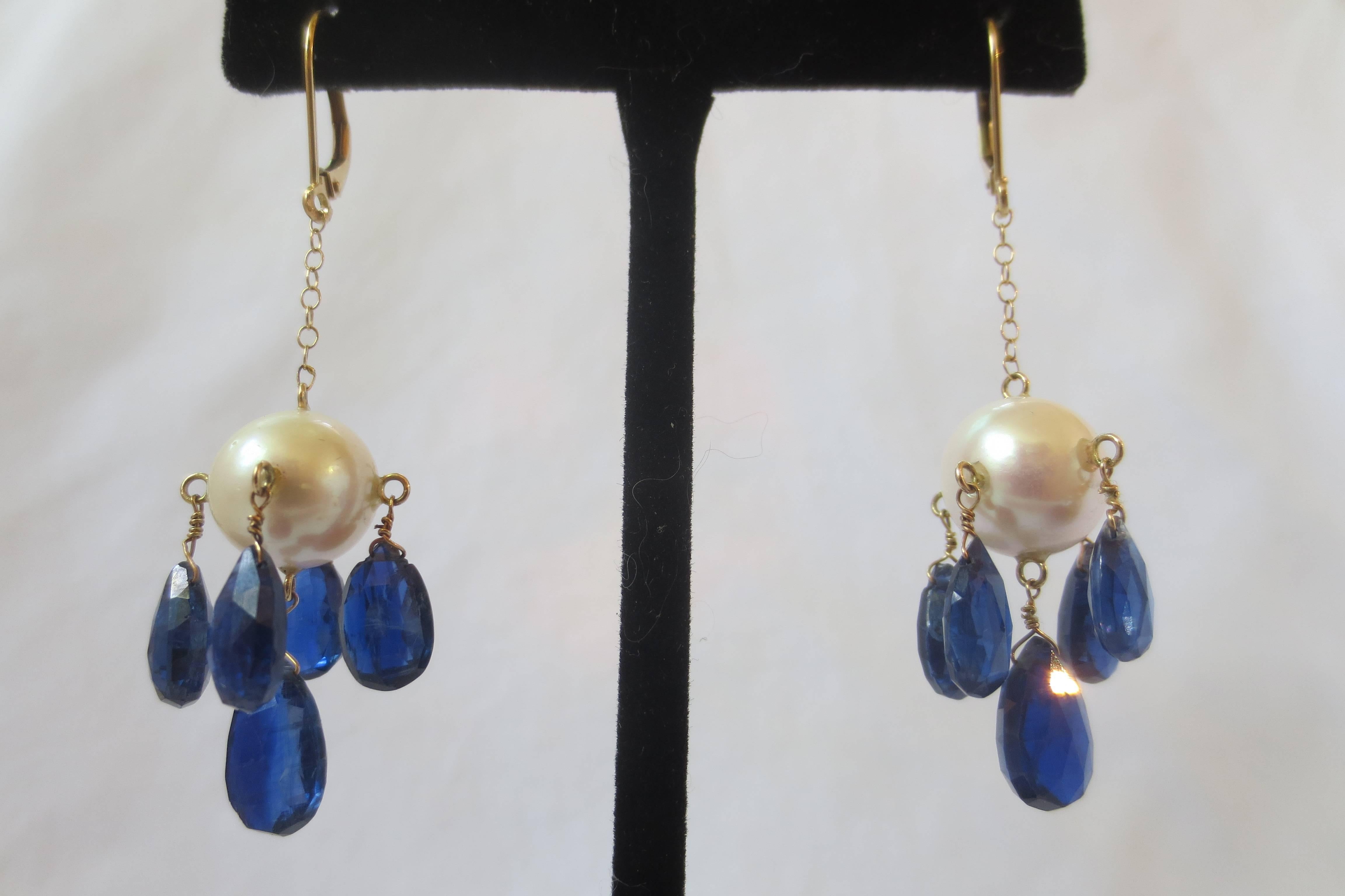 A large 10 mm round pearl is fitted with five kyanite, teardrop briolettes from gold findings. The briolettes are deep and lush, with a very rich, translucent blue that emanates from within. The whole earring is 2.25 inches long and dangles from a