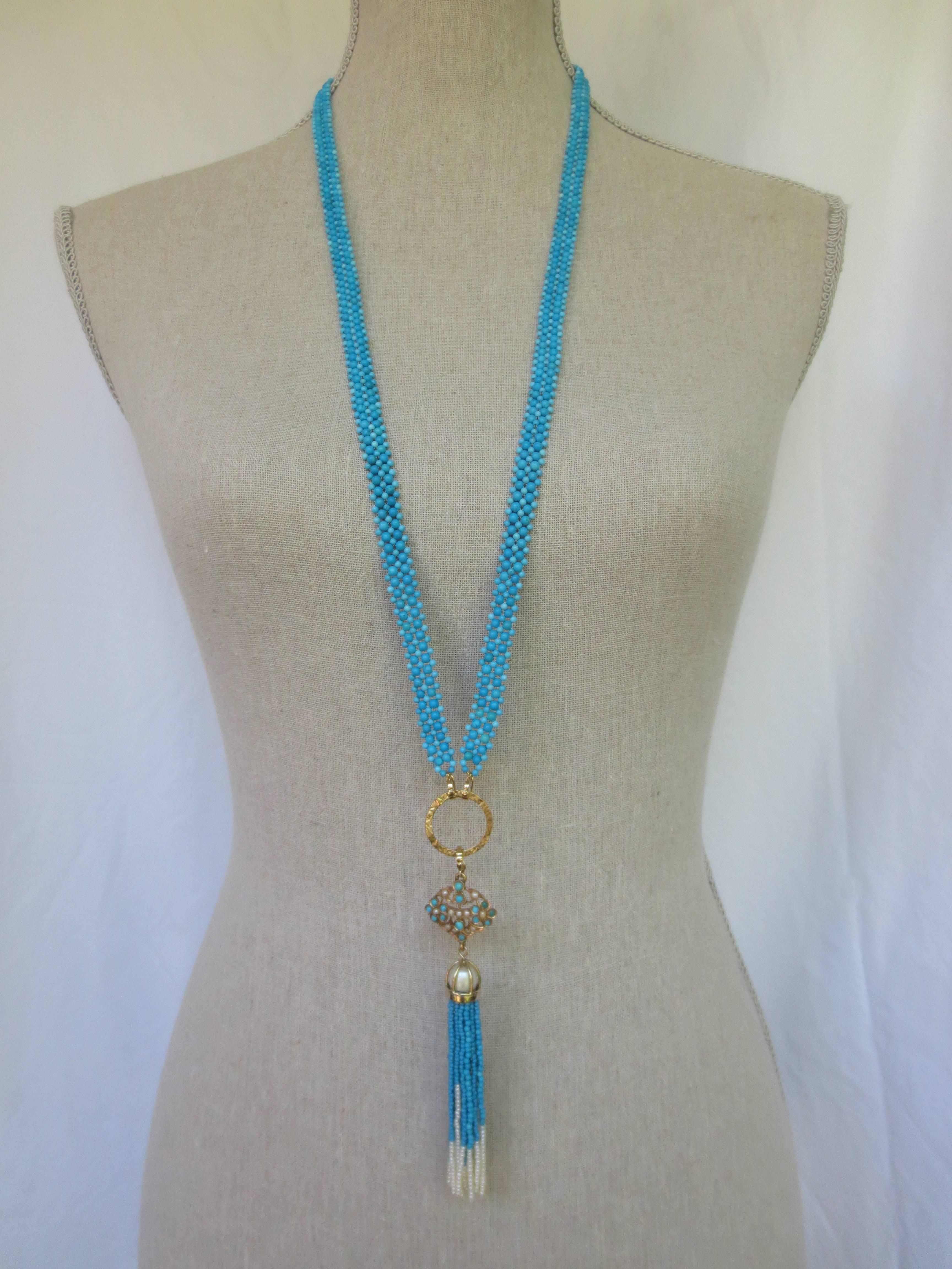 This unique necklace was created utilizing assorted size and hue turquoise beads and woven into a textured ribbon style that sits comfortably and lightly on the body. The vintage gold pendant, set with pearl and turquoise stones, served as the
