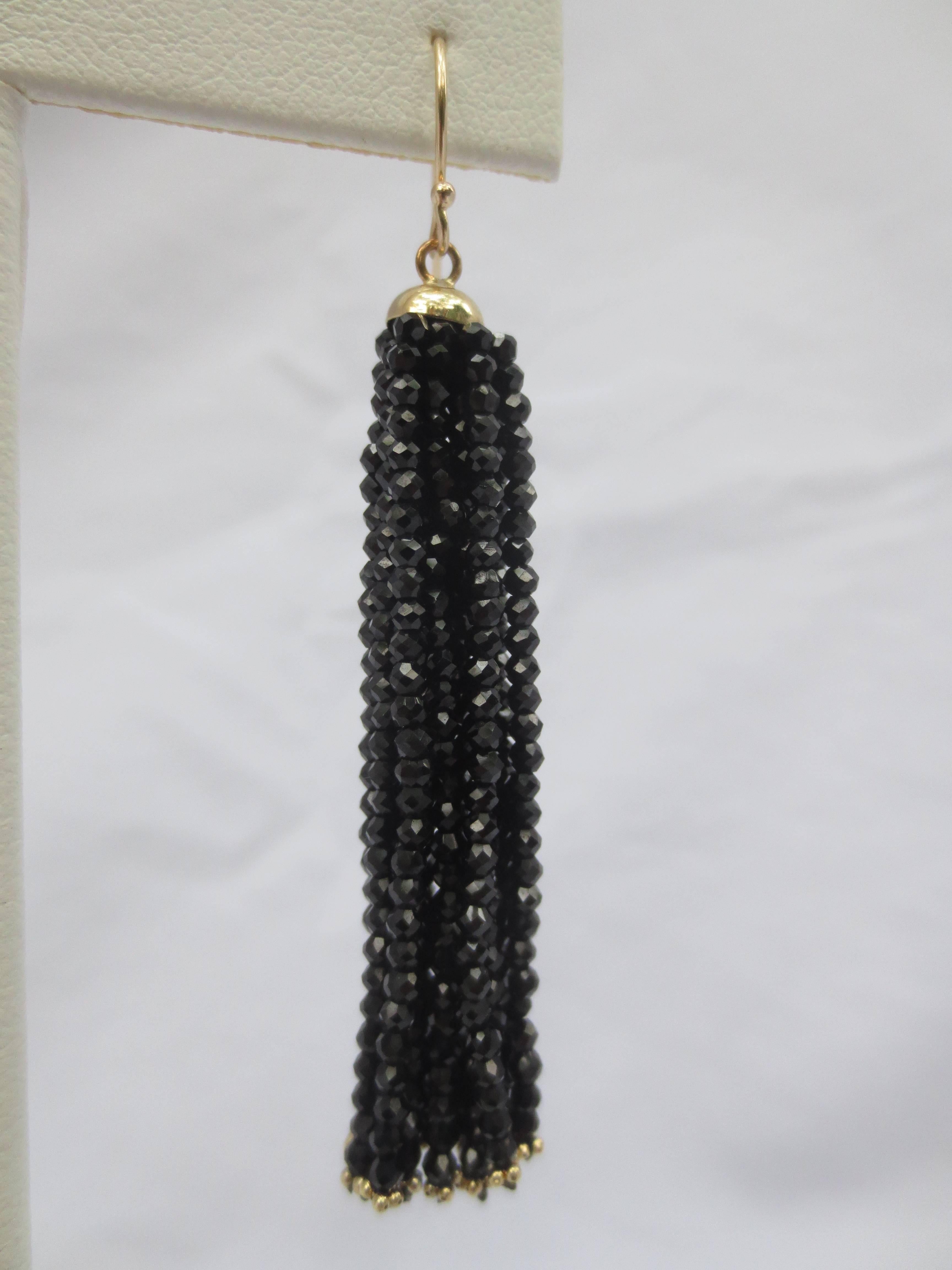 Measuring 2.5 inches long, these lightweight, elegant, and understated earrings will match well with any ensemble. Beaming from a 14 k Yellow Gold cup, the faceted Black Spinel beads reflect and dance in the light, and are finished with small Gold