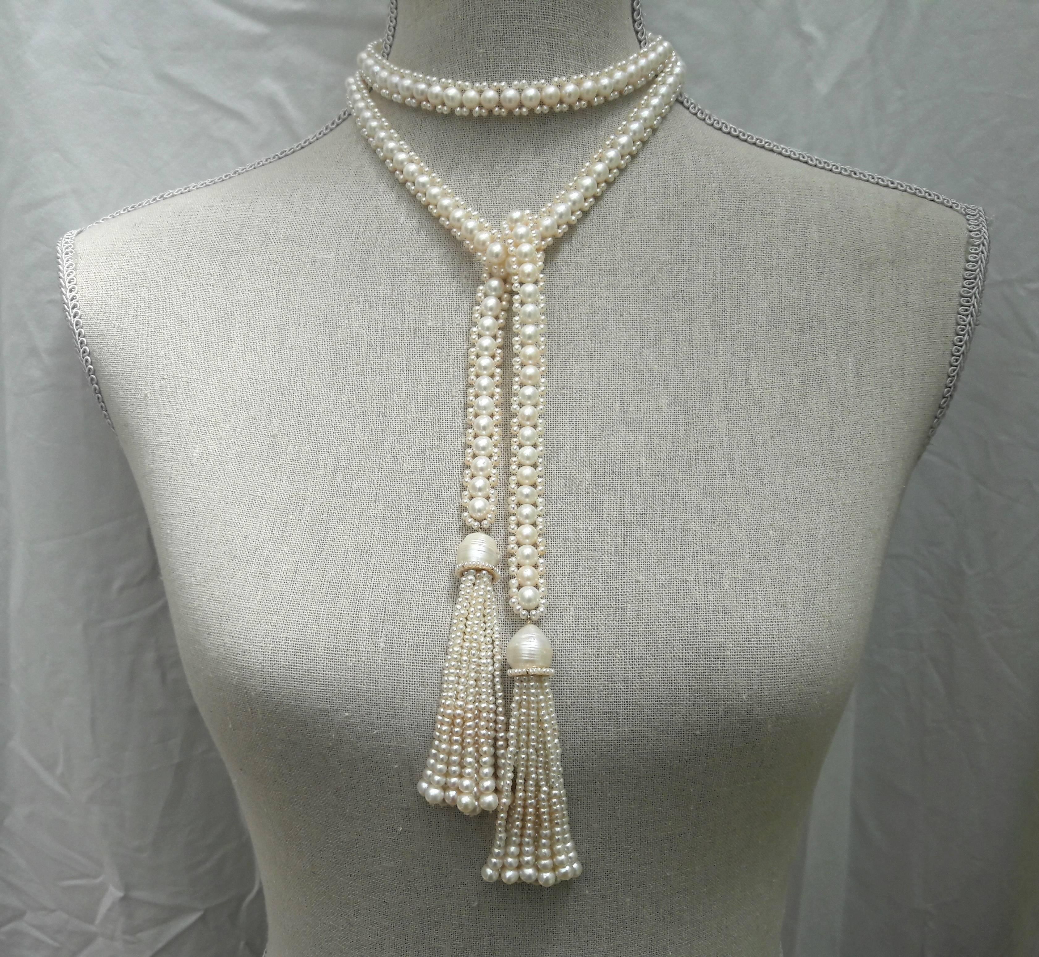Unique, intricately woven handmade rope sautoir made of 6.5mm and 2.5mm white cultured pearls. Tassels are topped with large baroque pearls, followed by a 14k yellow gold rondelle hand decorated with fine seed pearls and finished with subtlety
