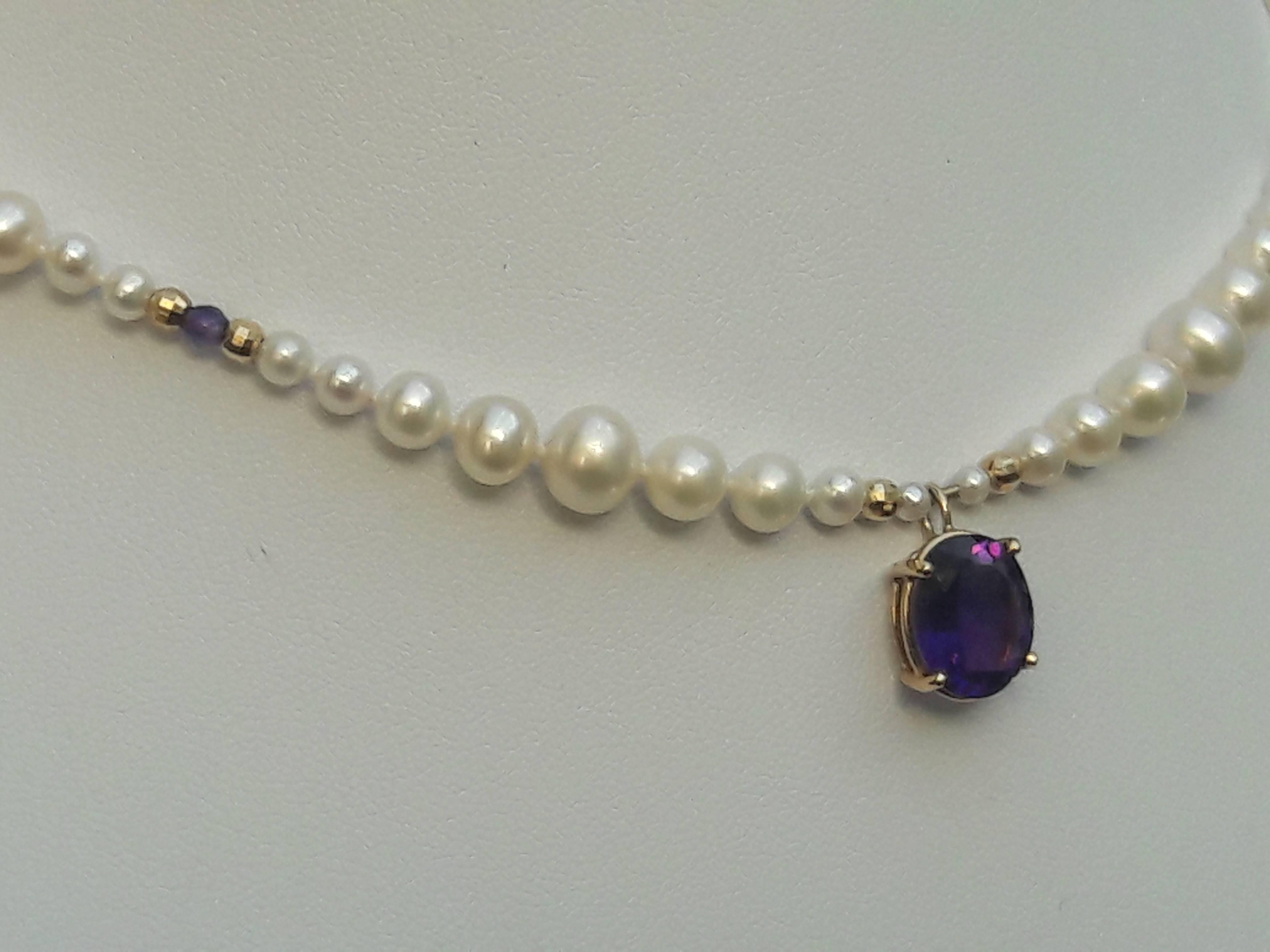 This unique and vibrant necklace is designed around clusters of graduated pearls that are divided by a small faceted amethyst bead and a pair of 14 K yellow gold faceted beads. Round and smooth pearls are 2 mm - 6 mm.

The center pendant is a