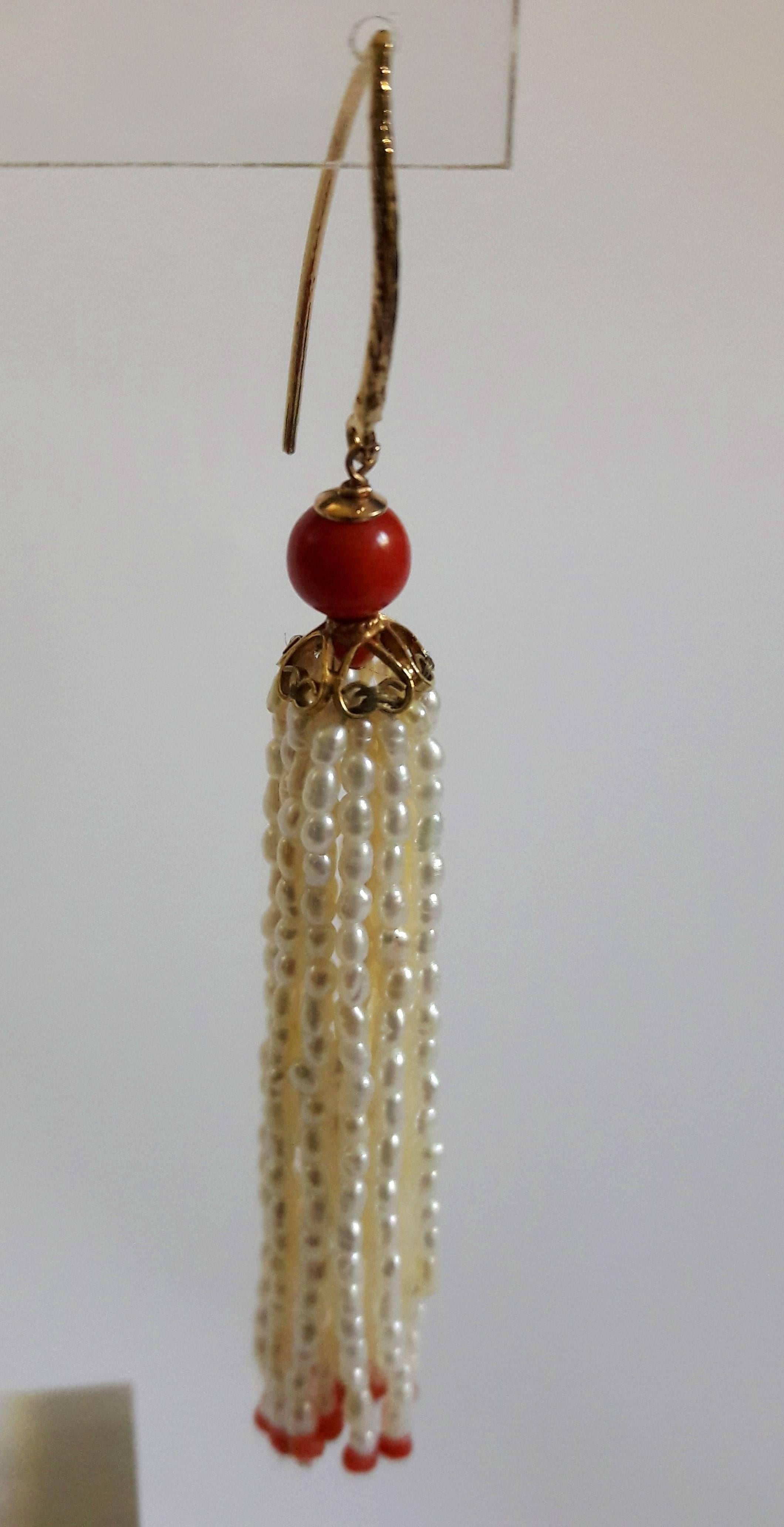These beautiful Pearl and Natural Coral Tassel earrings are composed of 18 strands each of fine rice pearls finished with small coral beads. Above the tassel, sits a 14 K yellow gold filigree cup and a 4 mm coral bead, from which the gold ear-wire