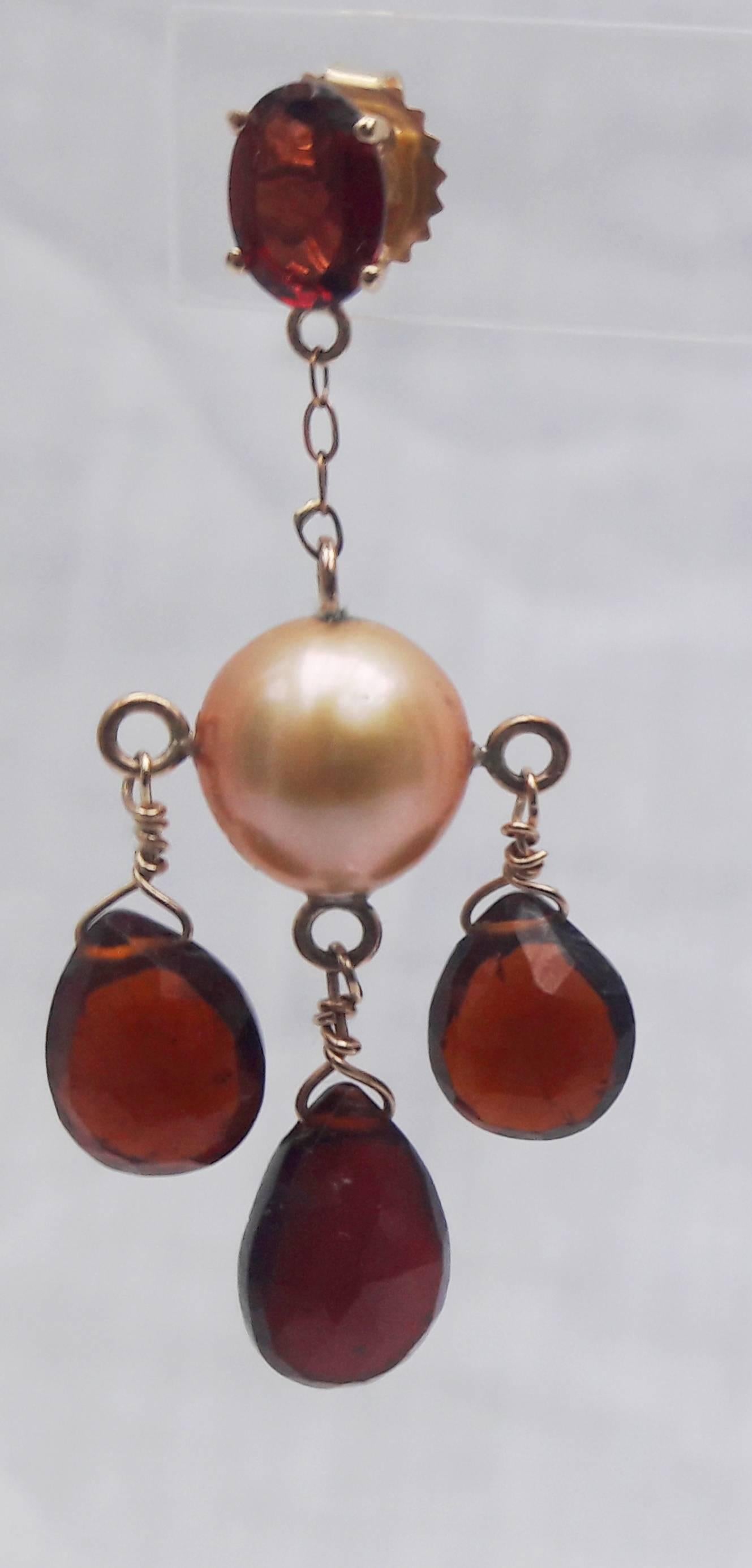 These beautiful earrings are centered around cream pearls with dangling red garnet drops, connected together with a 14k yellow gold chain and stud. The glowing cream cultured Chinese pearl is 8mm. The unique cream coloring highlights the brilliant,