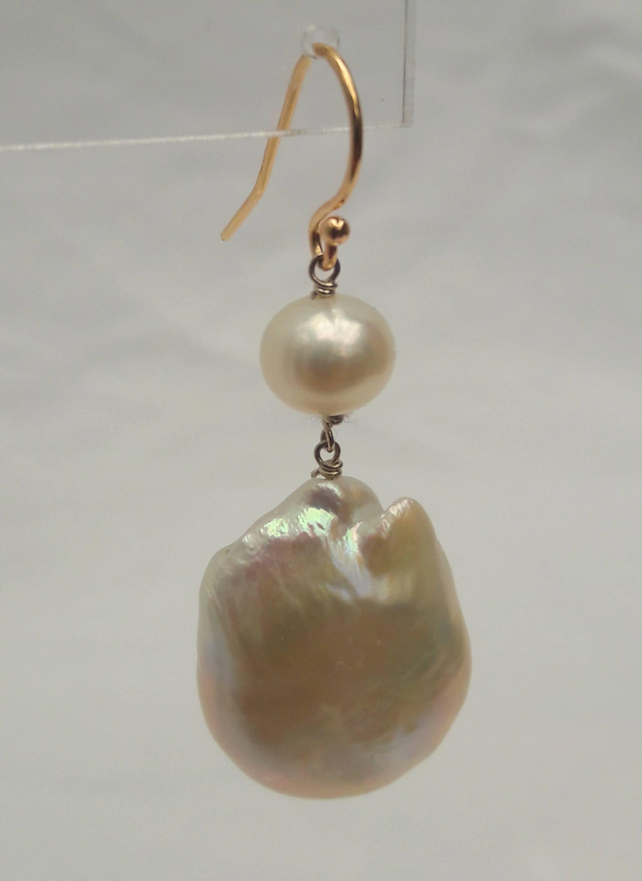 The round and lovely 6 mm round pearl on top, and a large, raw baroque bottom pearl on bottom. Each of these earrings make for a unique and elegant set of earrings. Secured with 14 K yellow gold hooks, these earrings pair well with anything.

top to