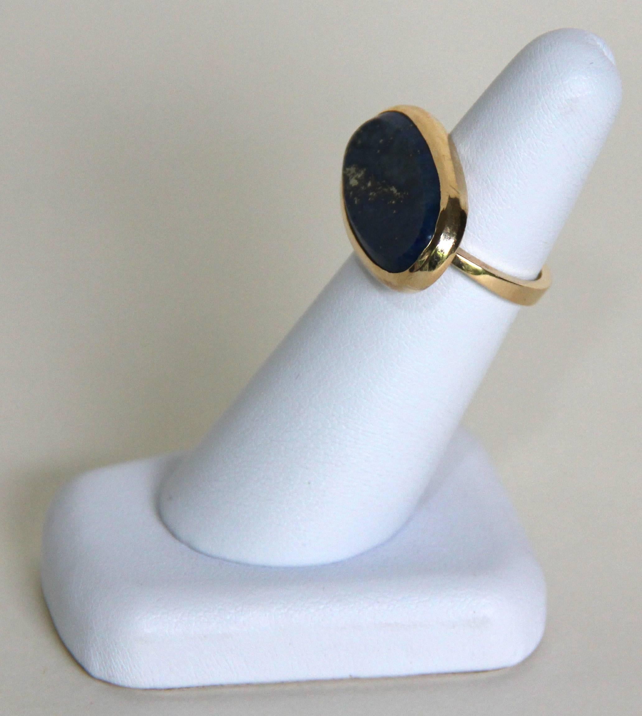 This original and stylish ring evokes the timelessness of antiquity. A large and smooth Lapis Lazuli oval stone is embedded in a 14K Yellow Gold ring. The ring is sized 7. The Lapis Lazuli oval stone measures 25mm long and 12mm wide. Made by Marina