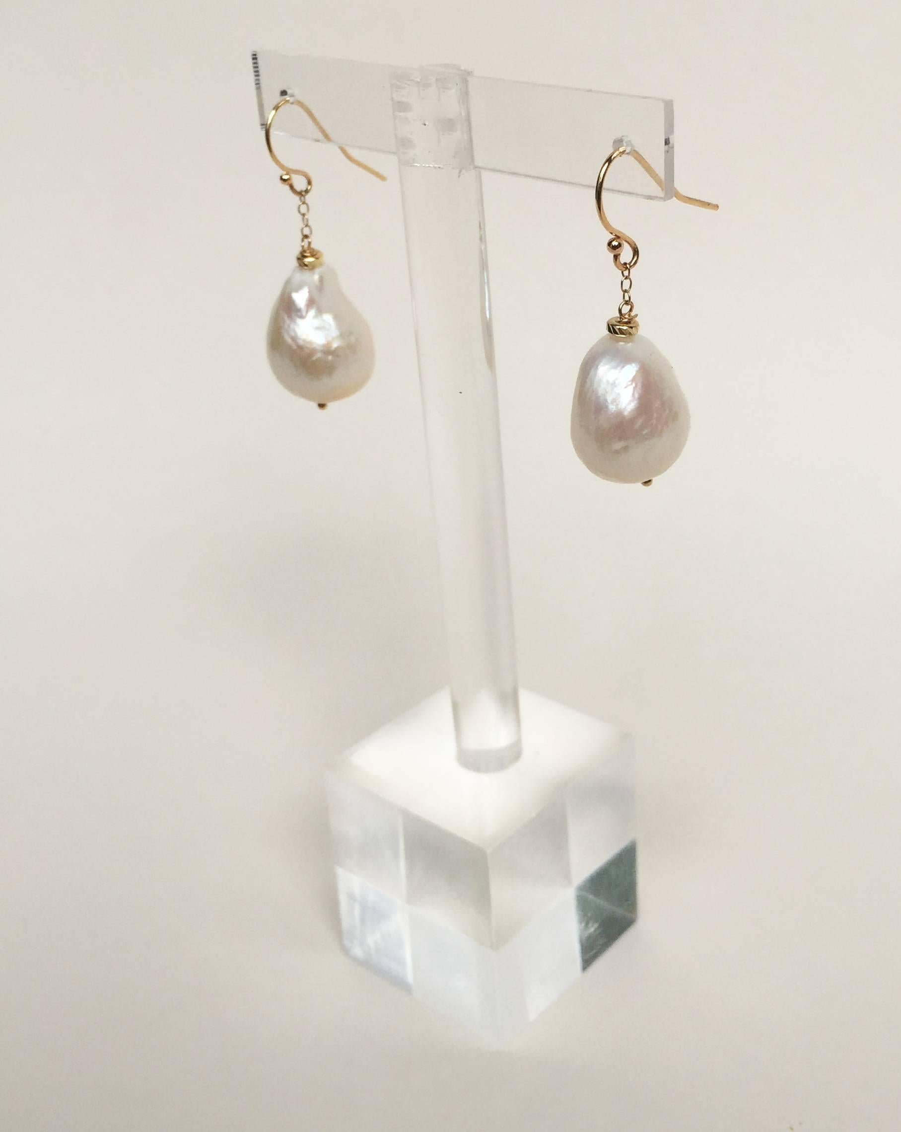 The raw baroque pearl (9mm x 7mm) hangs from a 14k yellow gold chain, accentuated by a 14k yellow gold hook. The earrings are 1.4 inches long, the perfect length to highlight the bone structure of the face. These classic earrings pair well with