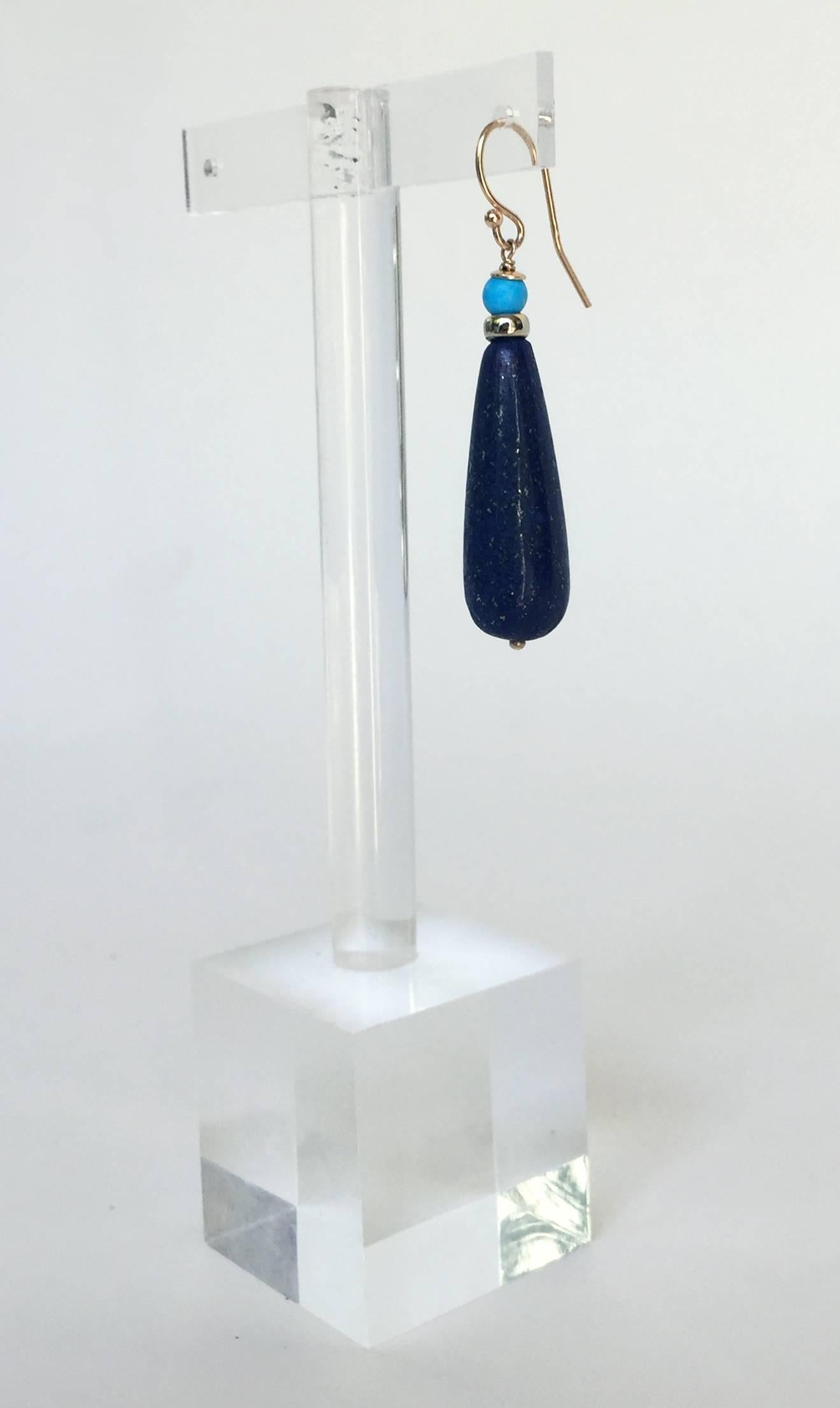 These elegant earrings showcase solid lapis lazuli drop beads. They are accented by 14K yellow gold and turquoise beads, bringing out the rich blue of the lapis lazuli . This composition is held by 14K yellow gold hooks, completing a Marina J