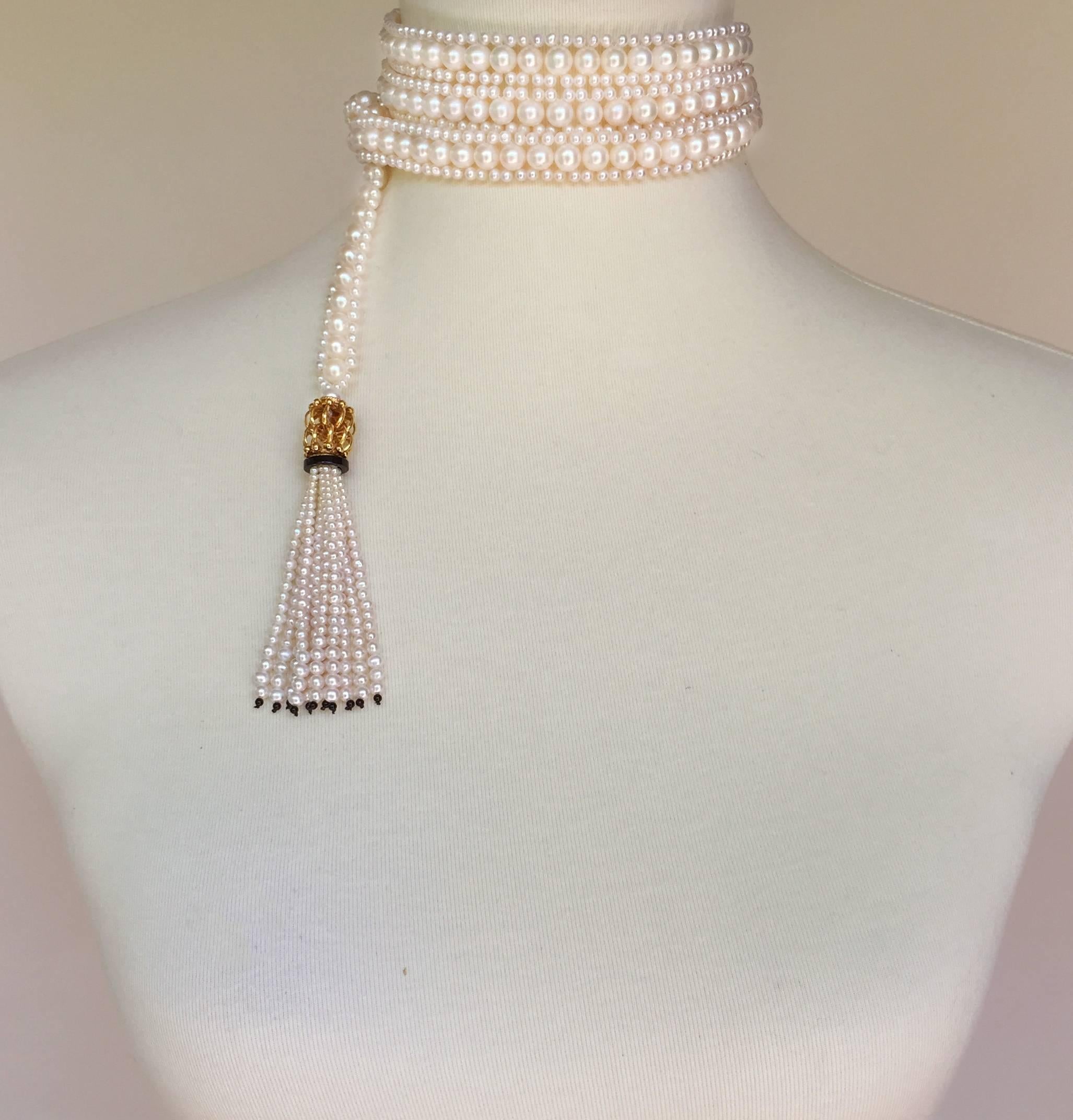 This intricately woven handmade rope sautoir is made of 6.5 mm and 2.5mm white pearls. The tassels are topped with large gold plated intertwined beads, followed by a onyx rondelles hand decorated with fine seed pearls and finished with subtlety