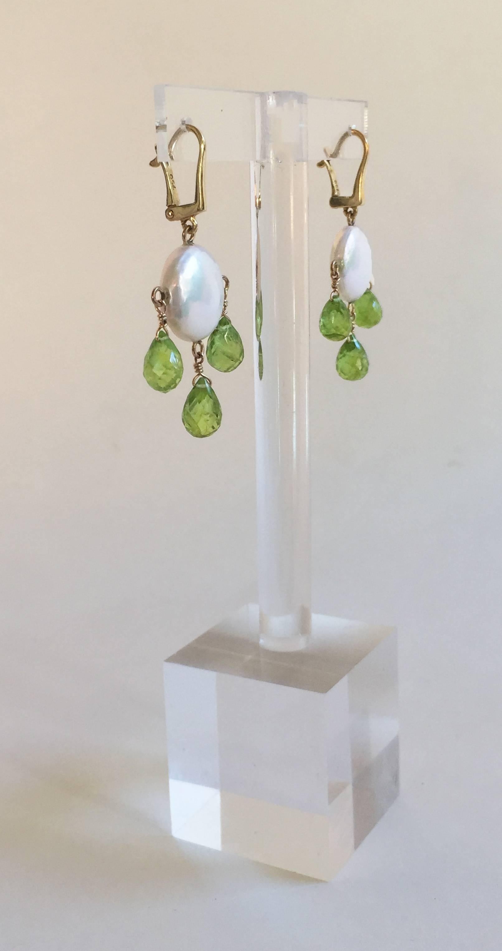 Sensual and playful coin pearl are accented by brilliant light green Peridot briolettes. The earrings measure at 1 3/4 inches. With 14k yellow gold findings, the earrings become more elegant and whimsical .