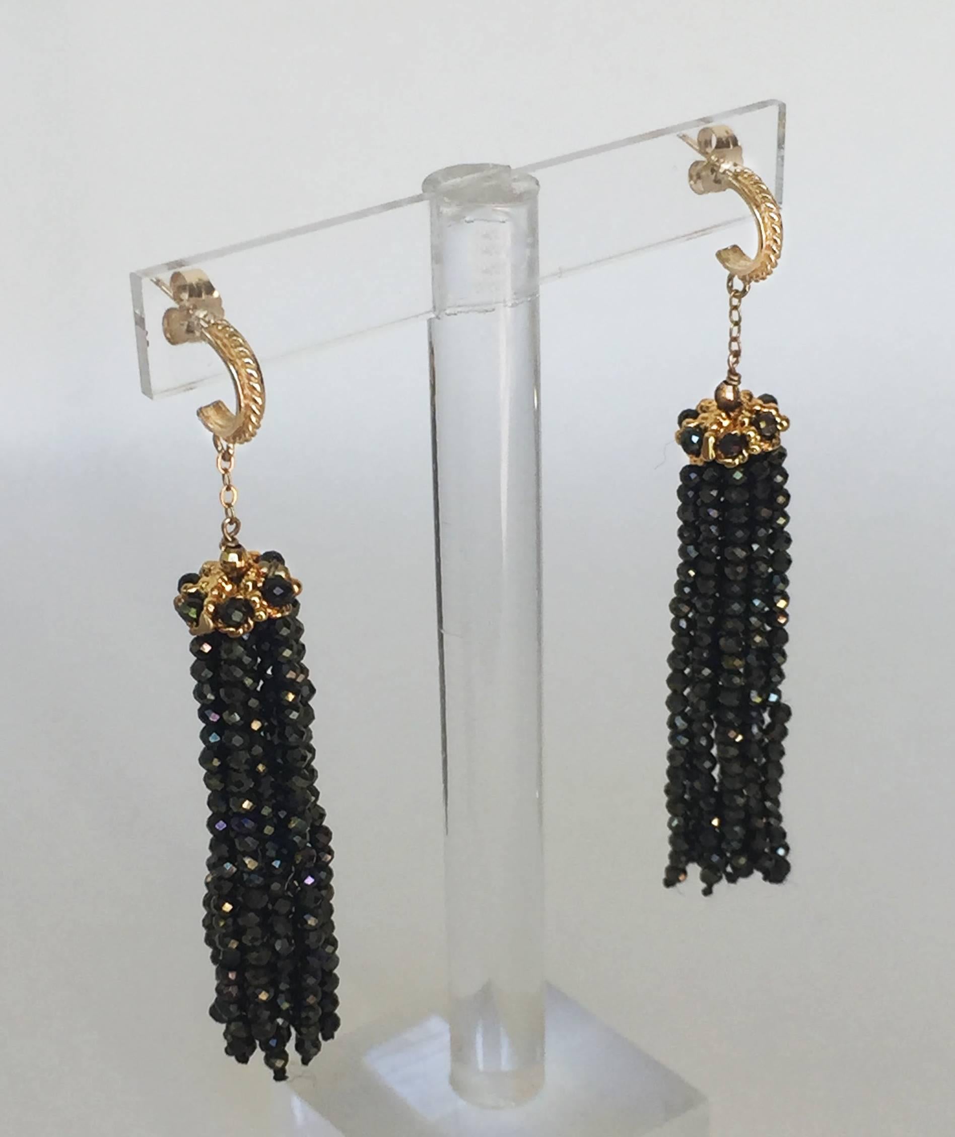 The black spinel beaded tassels sparkles a golden hue as it catches the light. At 2.5 inches, the earrings frame the face elegantly. At top the tassel is a 14k yellow gold cup with filigree and black spinel woven through. Completing the earrings are