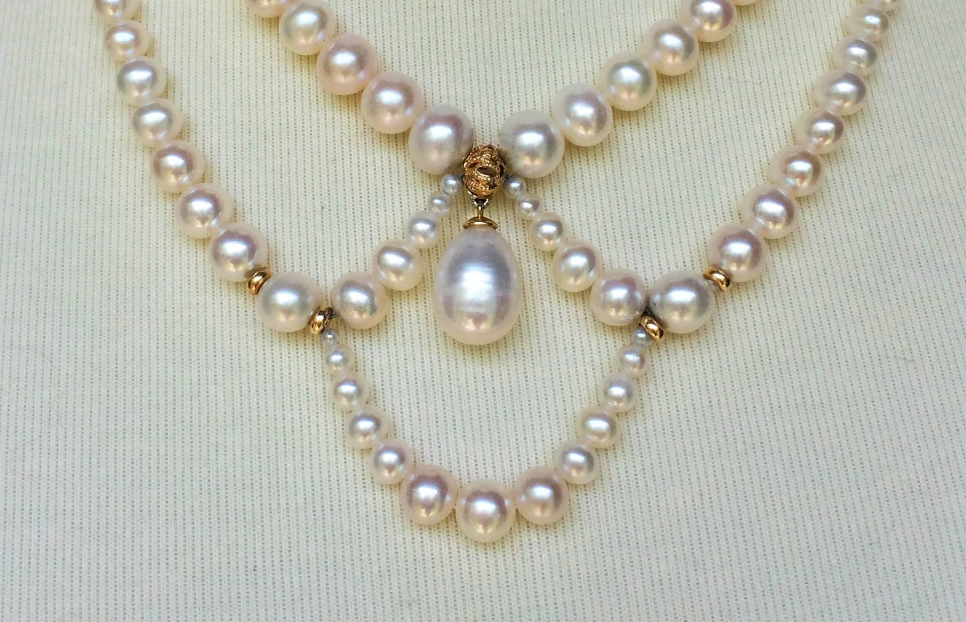 This elegant and timeless pearl necklace has graduated pearls with loops that accentuate the collar bone. At the center is a large tear drop pearl that brings the necklace together. 14k yellow gold beads highlight the pearls in the necklace. The 14k