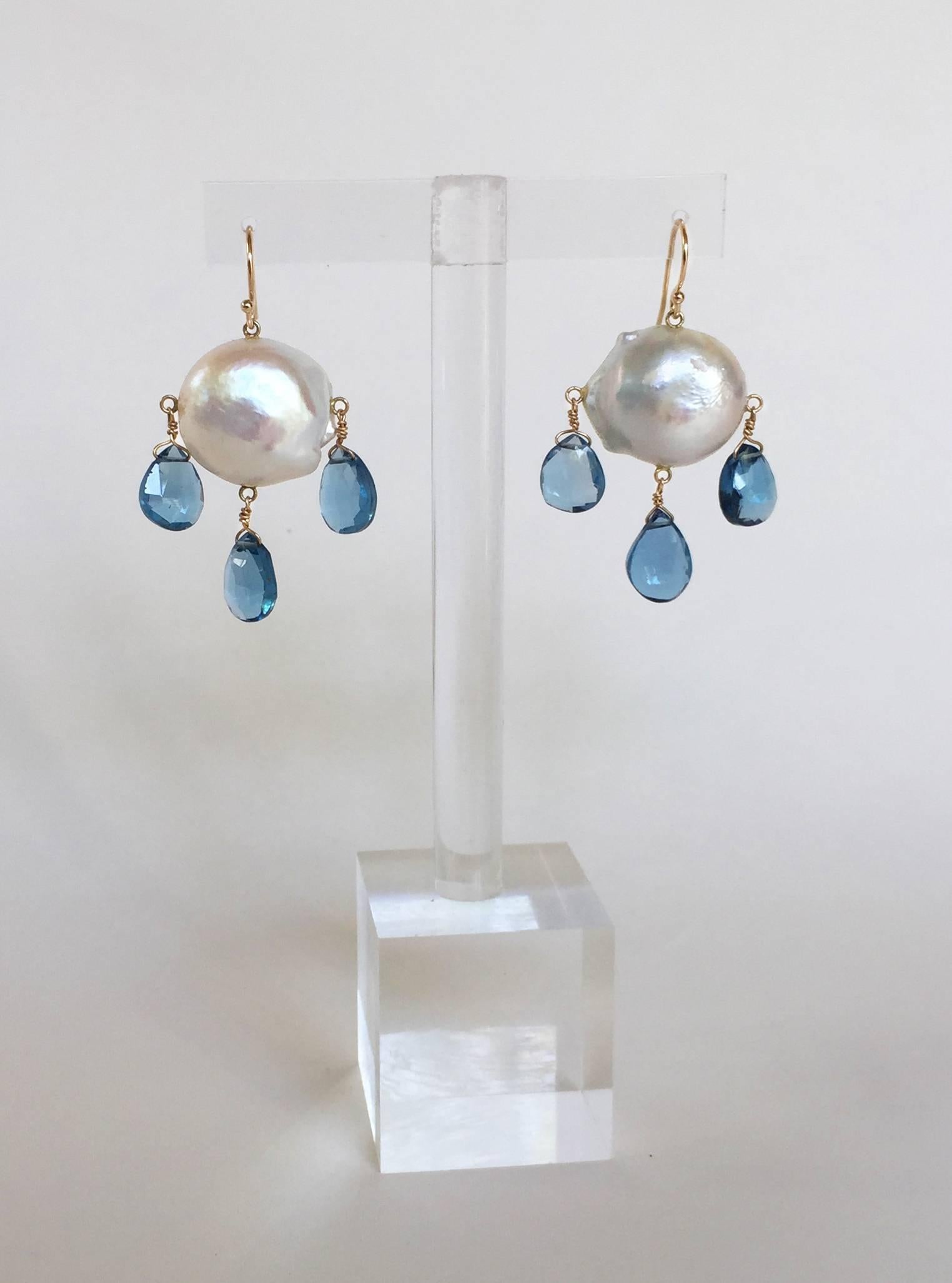Three London blue topaz droplets hang from a large round Baroque white pearl, by a 14k yellow gold hook and wiring. They hang perfectly at 1.65 inches. These beautiful and bold earrings add a graceful touch to your outfit. 