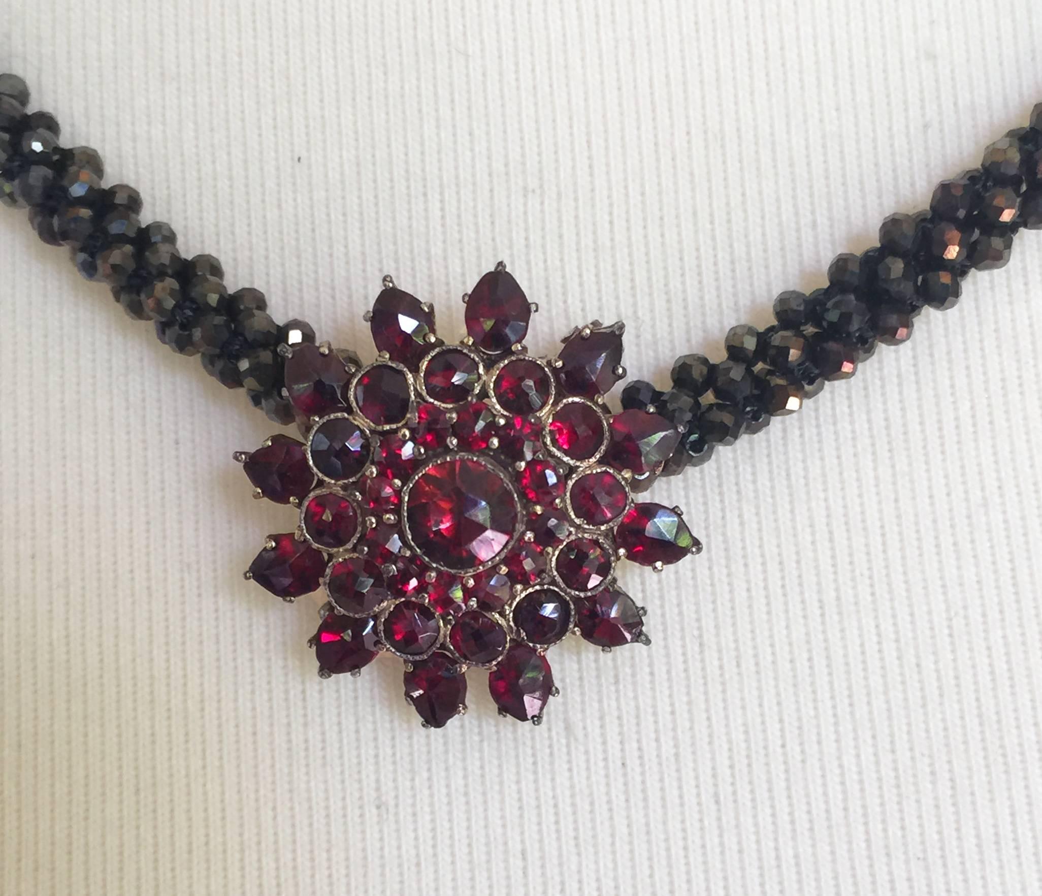 Made with hundreds of carefully selected, faceted copper toned black spinel beads and woven into a tight, three dimensional rope. The copper hue of the necklace matches well with the deep red garnet floral shaped vintage brooch. This necklace is